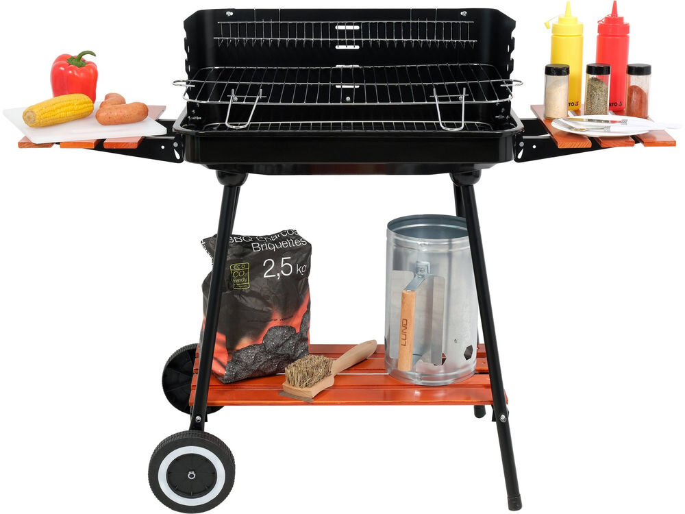 Grill węglowy na kółkach z półkami bocznymi, na których znajdują się przyprawy i sosy. Pod grillem widoczna jest torba z brykietem, szczotka do czyszczenia oraz metalowy pojemnik.