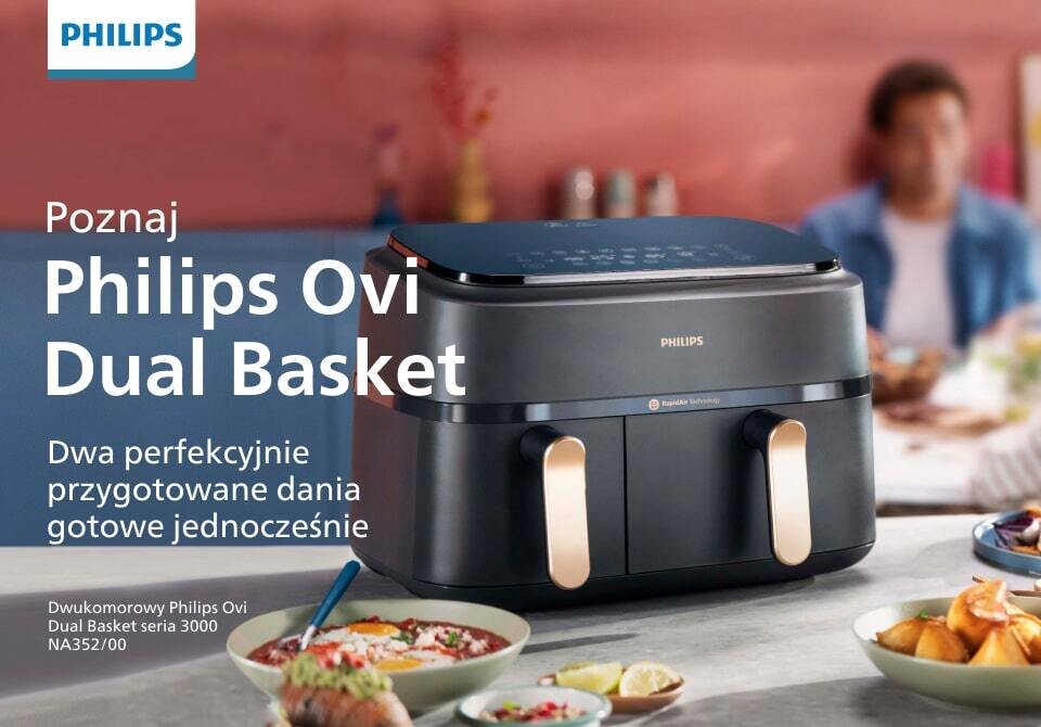 Na obrazie widoczna jest frytkownica beztłuszczowa z podwójnym koszem marki Philips, umieszczona na stole z jedzeniem. Tekst na obrazie: \'Poznaj Philips Ovi Dual Basket Dwa perfekcyjnie przygotowane dania gotowe jednocześnie Dwukomorowy Philips Ovi Dual Basket seria 3000 NA352/00\'.
