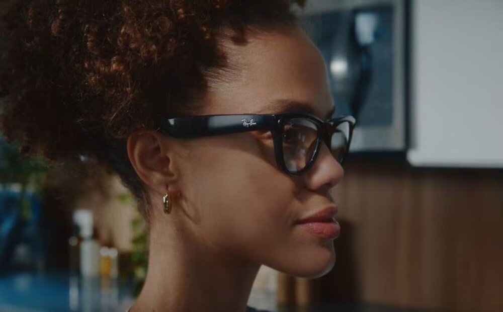 Osoba nosi czarne okulary z połyskiem, na których widoczne jest logo \'Ray-Ban\'.