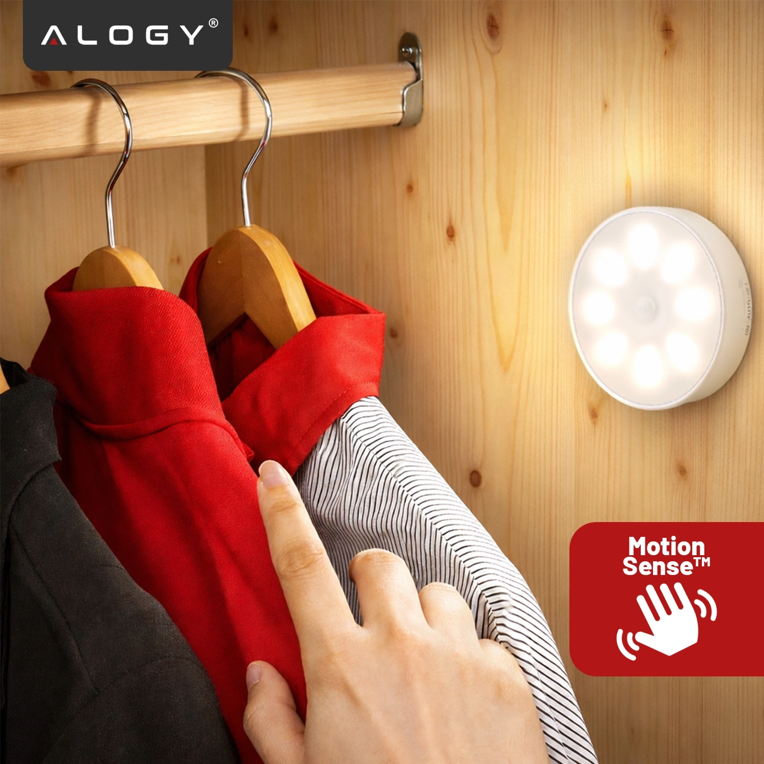 Na drewnianej ścianie wisi okrągła lampka LED, obok której znajdują się ubrania na wieszakach. W lewym górnym rogu widoczne jest logo \'ALOGY\', a w prawym dolnym rogu znajduje się ikona z napisem \'Motion Sense™\'.