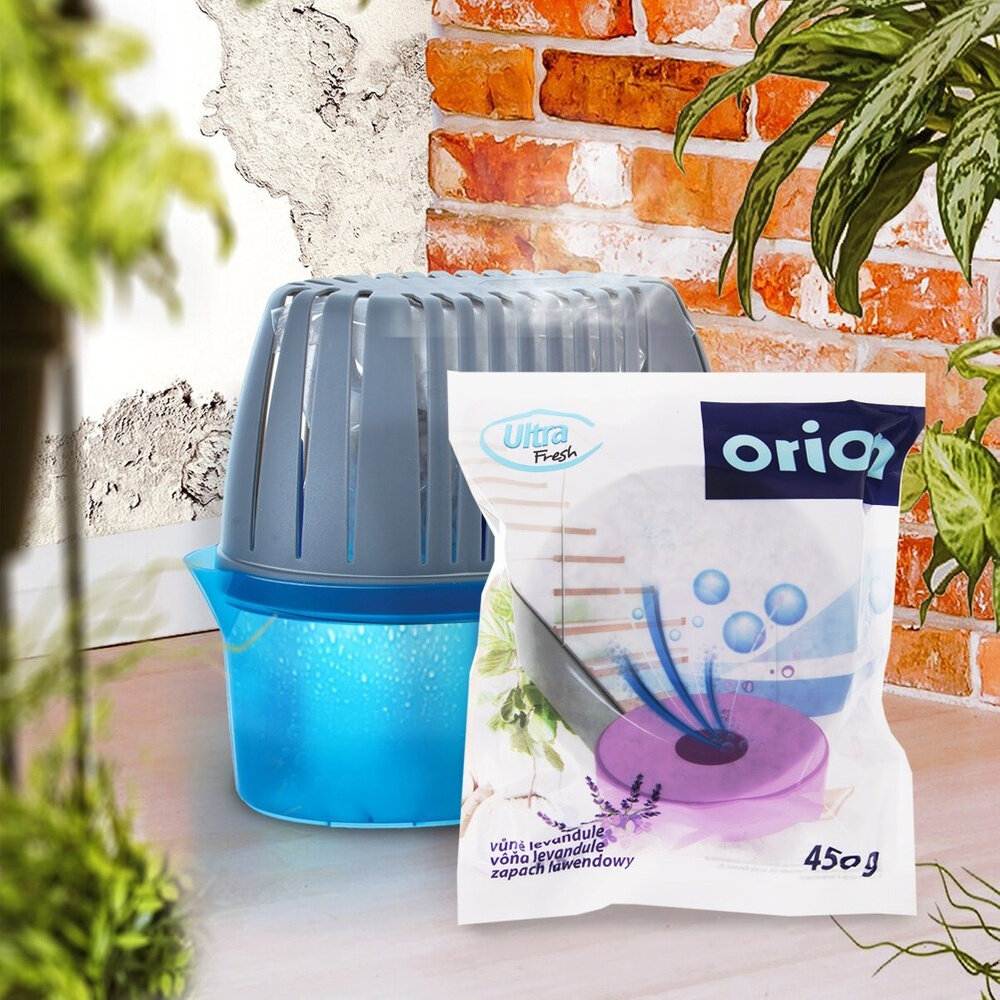 Na obrazie widoczny jest pochłaniacz wilgoci z niebieskim pojemnikiem oraz opakowanie lawendowego wkładu Ultra Fresh 450g z napisem \'orion\'. W tle znajduje się ściana z cegieł i rośliny.