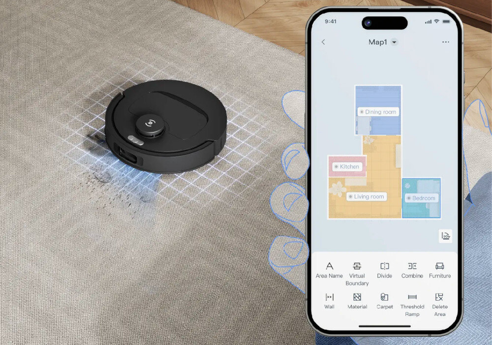 Na dywanie znajduje się czarny robot sprzątający, a obok widoczny jest ekran smartfona z aplikacją pokazującą mapę pomieszczeń: Dining room, Kitchen, Living room, Bedroom. Na ekranie aplikacji widoczne są opcje: Area Name, Virtual Boundary, Divide, Combine, Furniture, Wall, Material, Carpet, Threshold Ramp, Delete Area.