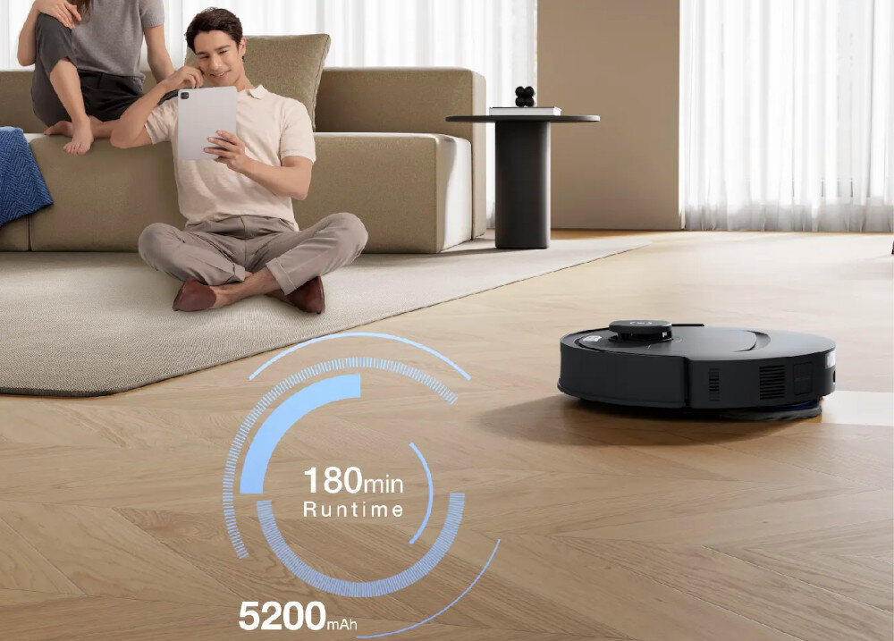 Na drewnianej podłodze znajduje się robot sprzątający. Obok widoczny jest napis \'180 min Runtime 5200 mAh\'.