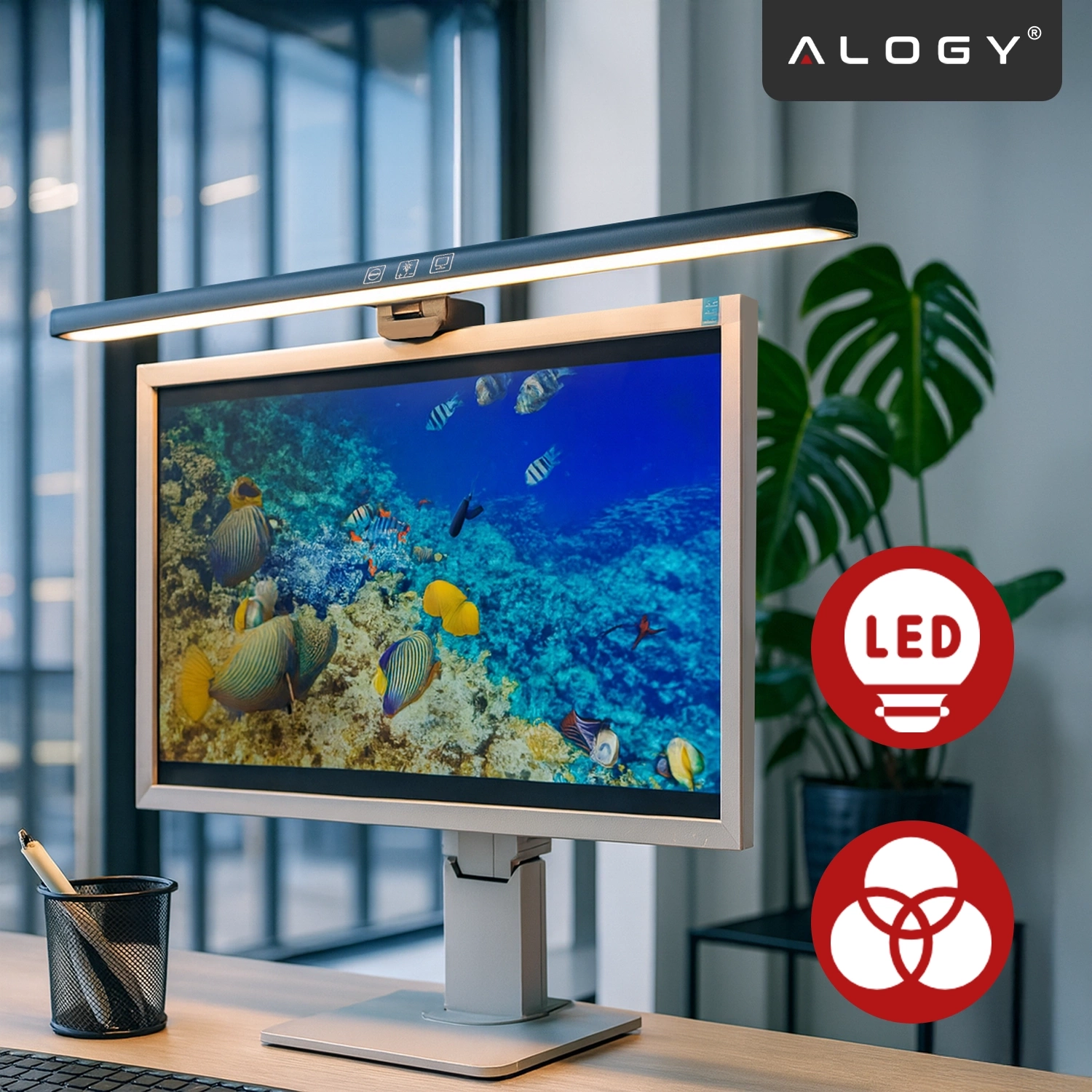 Na biurku stoi monitor z wyświetlanym obrazem rafy koralowej, nad którym zamontowana jest lampka LED. W rogu widoczne jest logo \'ALOGY\' oraz dwa czerwone symbole z napisami \'LED\'.