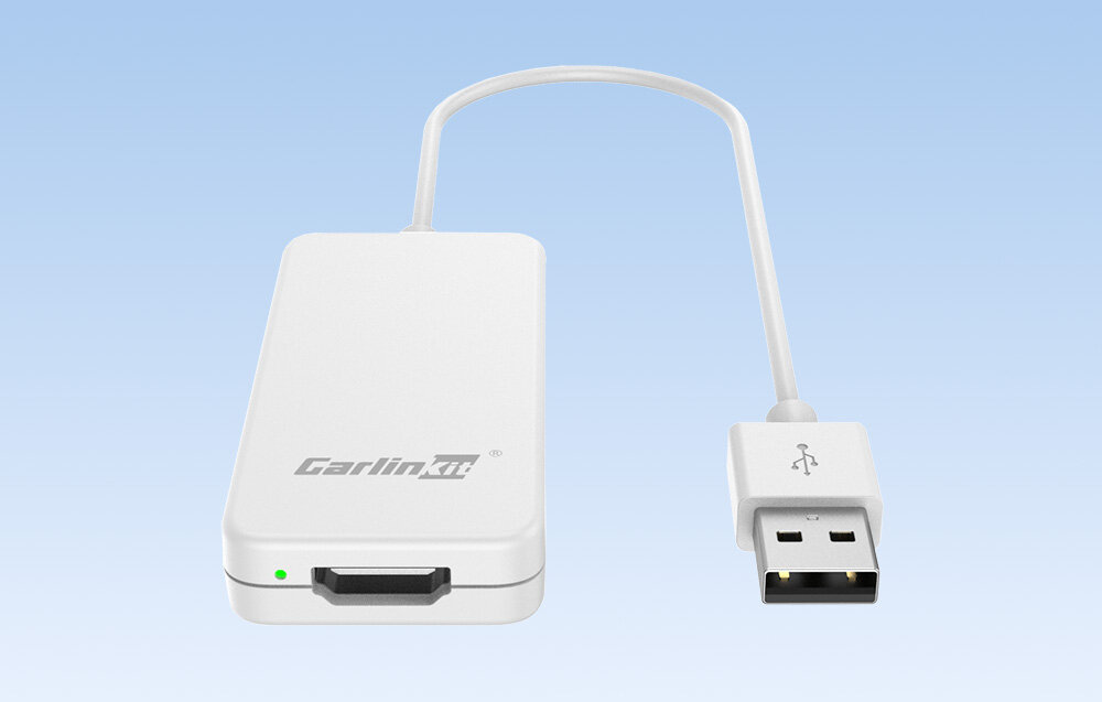 Biały adapter z logo \'Carlinkit\' i krótkim kablem zakończonym wtykiem USB, na tle jasnoniebieskiego gradientu.