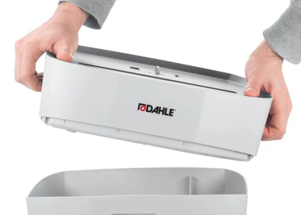 Niszczarka DAHLE PaperSAFE Dwie dłonie podnoszące górną część niszczarki z mechanizmem tnącym i logo od dolnego pojemnika na ścinki