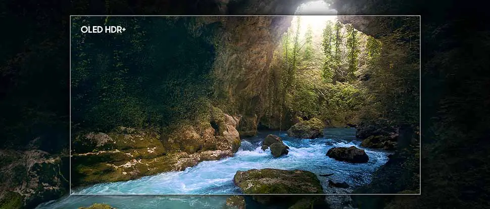 970x415 s90f picture quality oled hdr Obraz przedstawia malowniczy krajobraz z rzeką płynącą przez skalisty wąwóz, otoczony bujną zielenią. W lewym górnym rogu widoczny jest napis \'OLED HDR+\'.