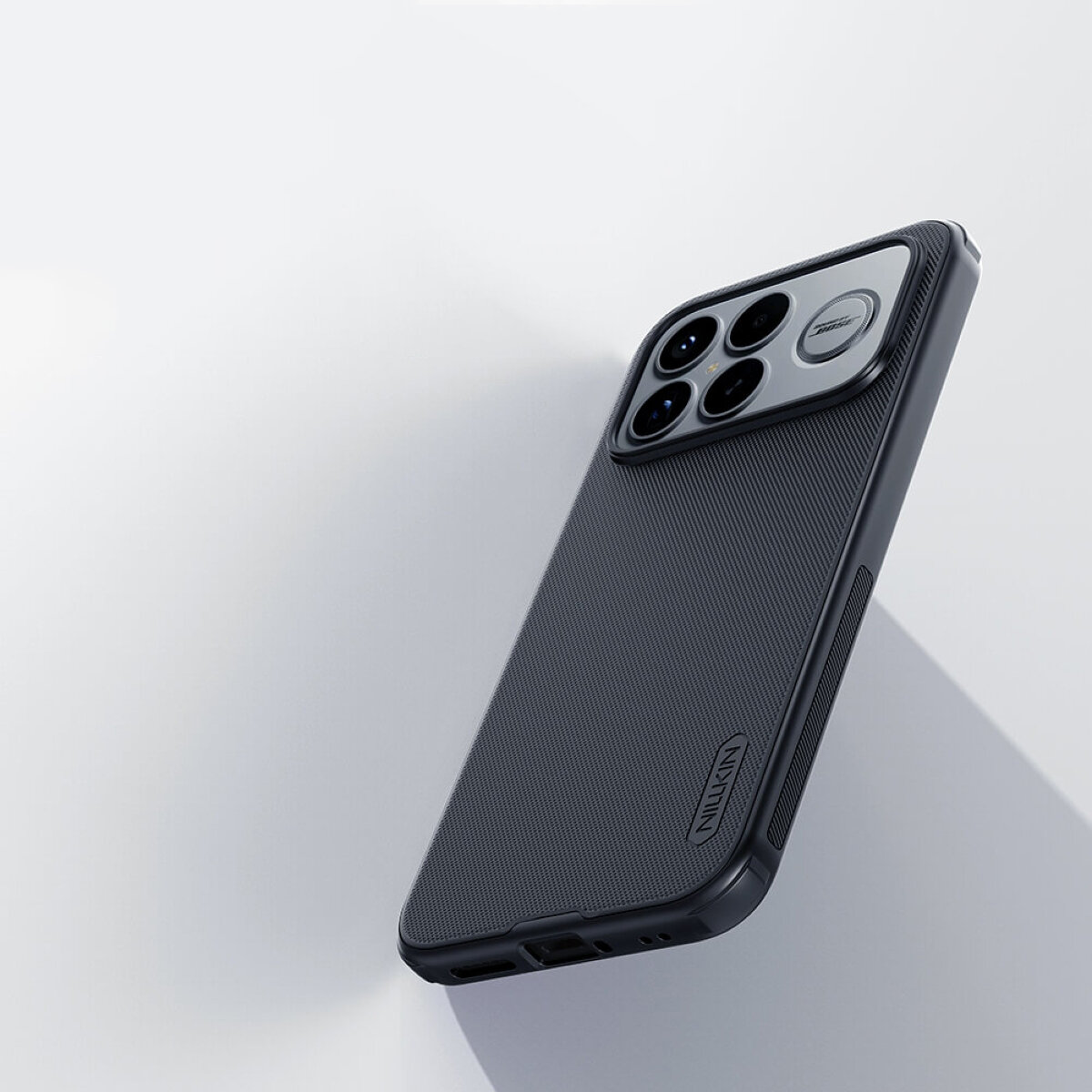 Na obrazie widoczne jest ciemne etui na telefon z teksturą, z wycięciem na aparat z czterema obiektywami. Na etui znajduje się logo \'Nillkin\'.