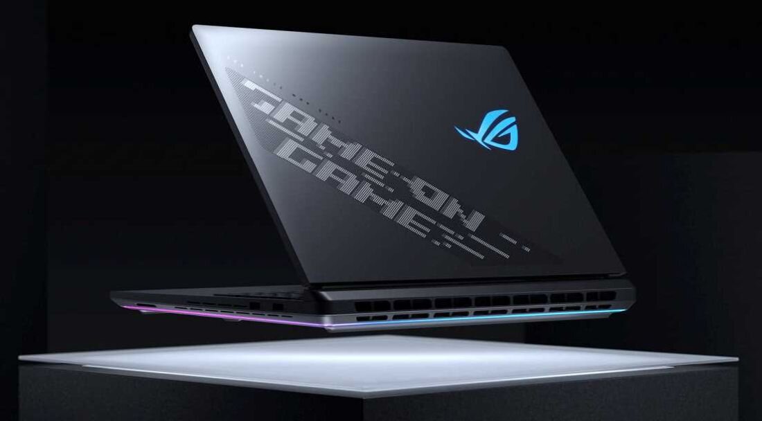 Laptop z podświetlanym logo i napisem \'GAME ON\' na pokrywie, umieszczony na podświetlonej platformie. Obudowa ma ciemny kolor z widocznymi otworami wentylacyjnymi.