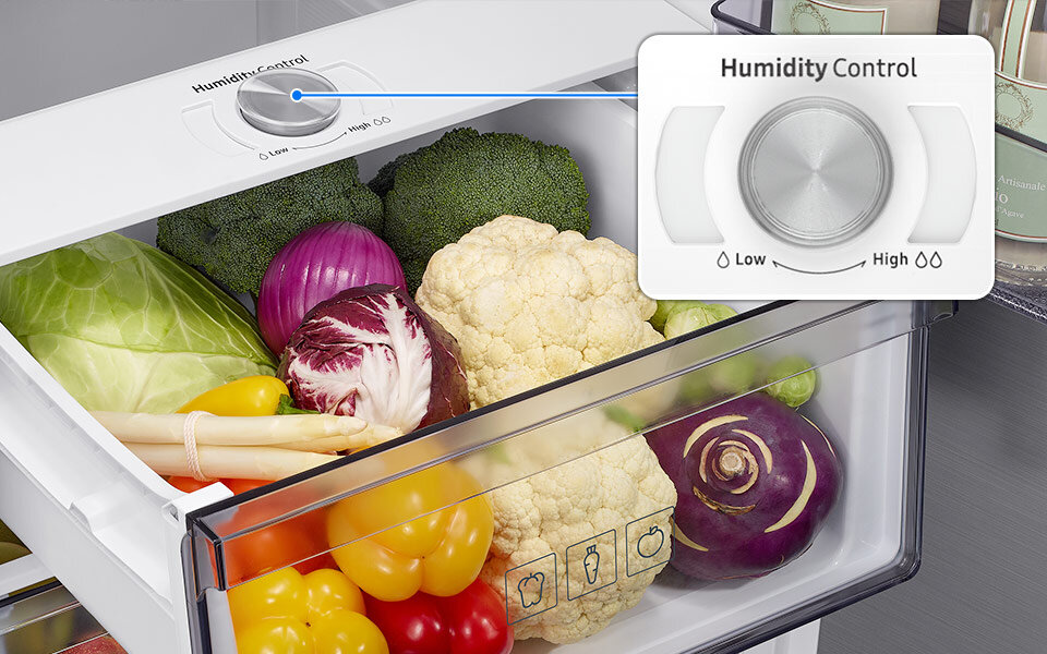 Szuflada na owoce i warzywa Wnętrze lodówki z szufladą wypełnioną warzywami, takimi jak kapusta, brokuły, kalafior i papryka. Widoczny jest panel \'Humidity Control\' z pokrętłem ustawionym na \'Low\'.