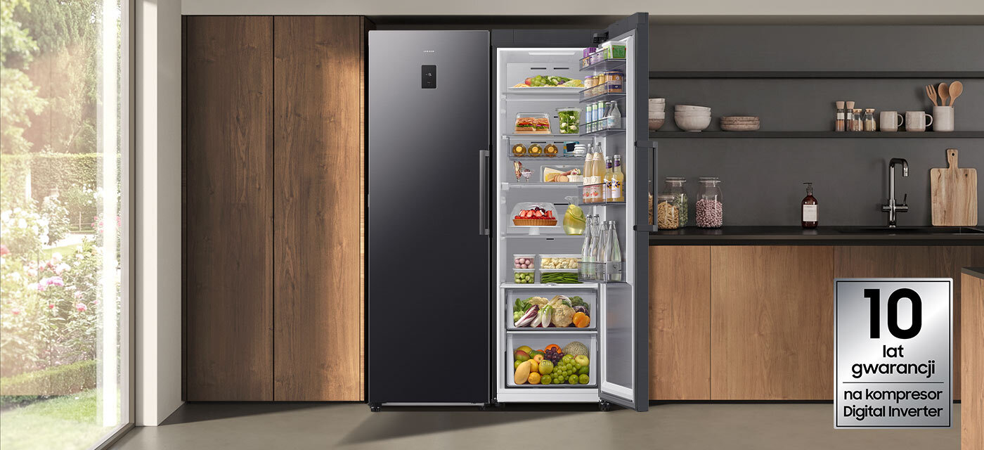 Chłodziarka z kompresorem Digital Inverter W kuchni znajduje się otwarta lodówka w grafitowym kolorze, wypełniona różnorodnymi produktami spożywczymi. Obok widoczny jest napis: \'10 lat gwarancji na kompresor Digital Inverter\'.