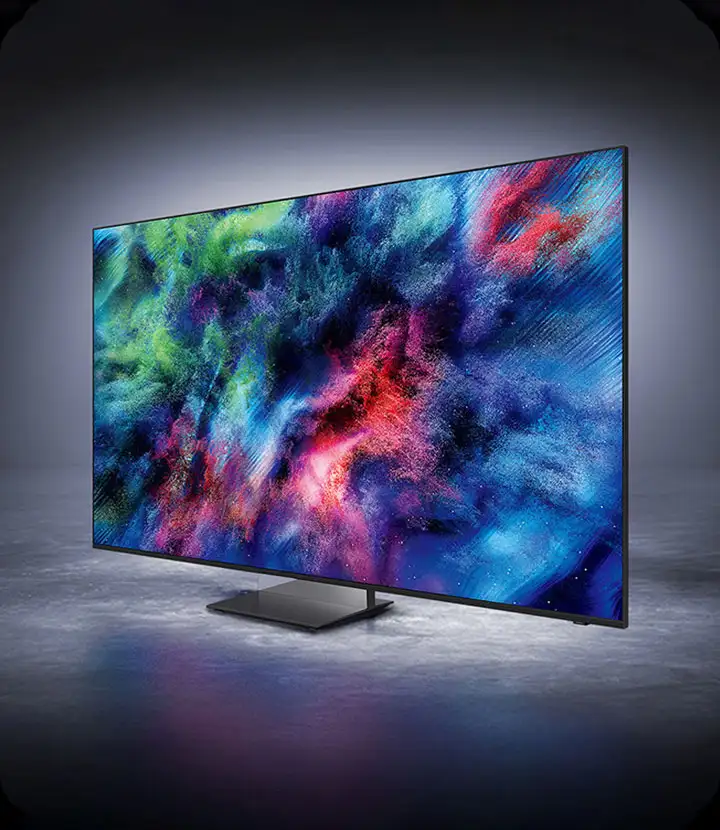 2026-micro-rgb-infinity-air-design-mo 720x830 Telewizor z dużym ekranem wyświetlający kolorową, abstrakcyjną grafikę. Urządzenie stoi na prostokątnej podstawie na szarej powierzchni.