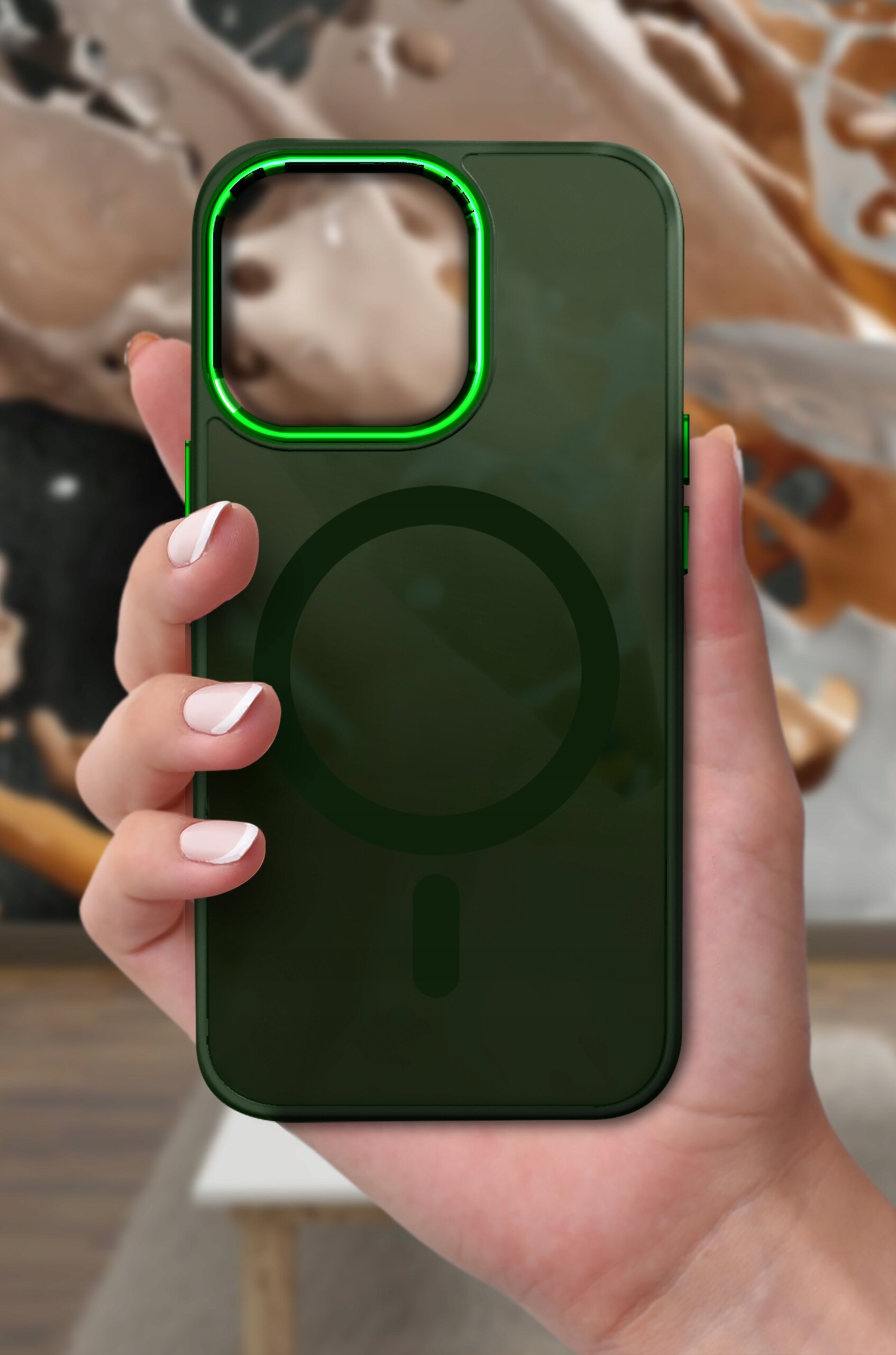 Osoba trzyma ciemnozielone etui na telefon z widocznym okrągłym wzorem na środku i zielonym obramowaniem wokół otworu na aparat.