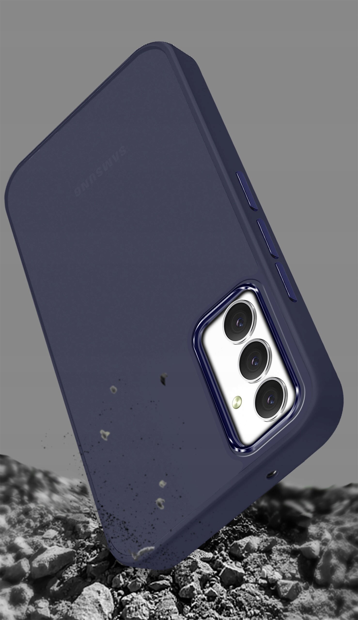 Na obrazie widoczne jest matowe etui na telefon w kolorze granatowym, z trzema wycięciami na aparaty. Etui leży na tle przypominającym kamienie lub żwir.