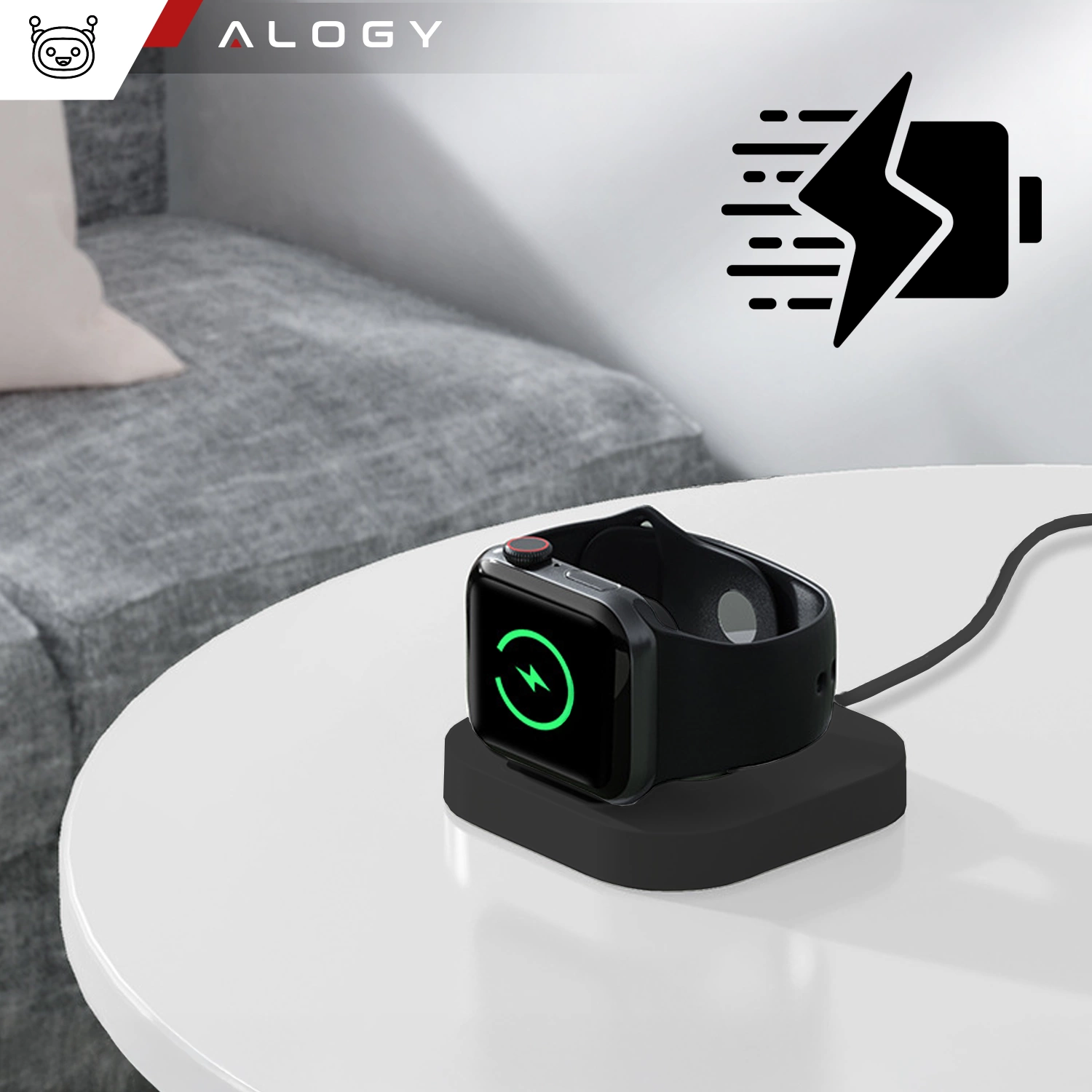 Na białym stole znajduje się czarna ładowarka indukcyjna z zegarkiem Apple Watch, który pokazuje ikonę ładowania. W lewym górnym rogu widoczne jest logo \'ALOGY\'.