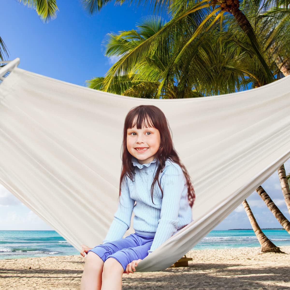 Na obrazie widać dziecko siedzące na beżowym hamaku zawieszonym między palmami na plaży. W tle znajduje się morze i błękitne niebo.