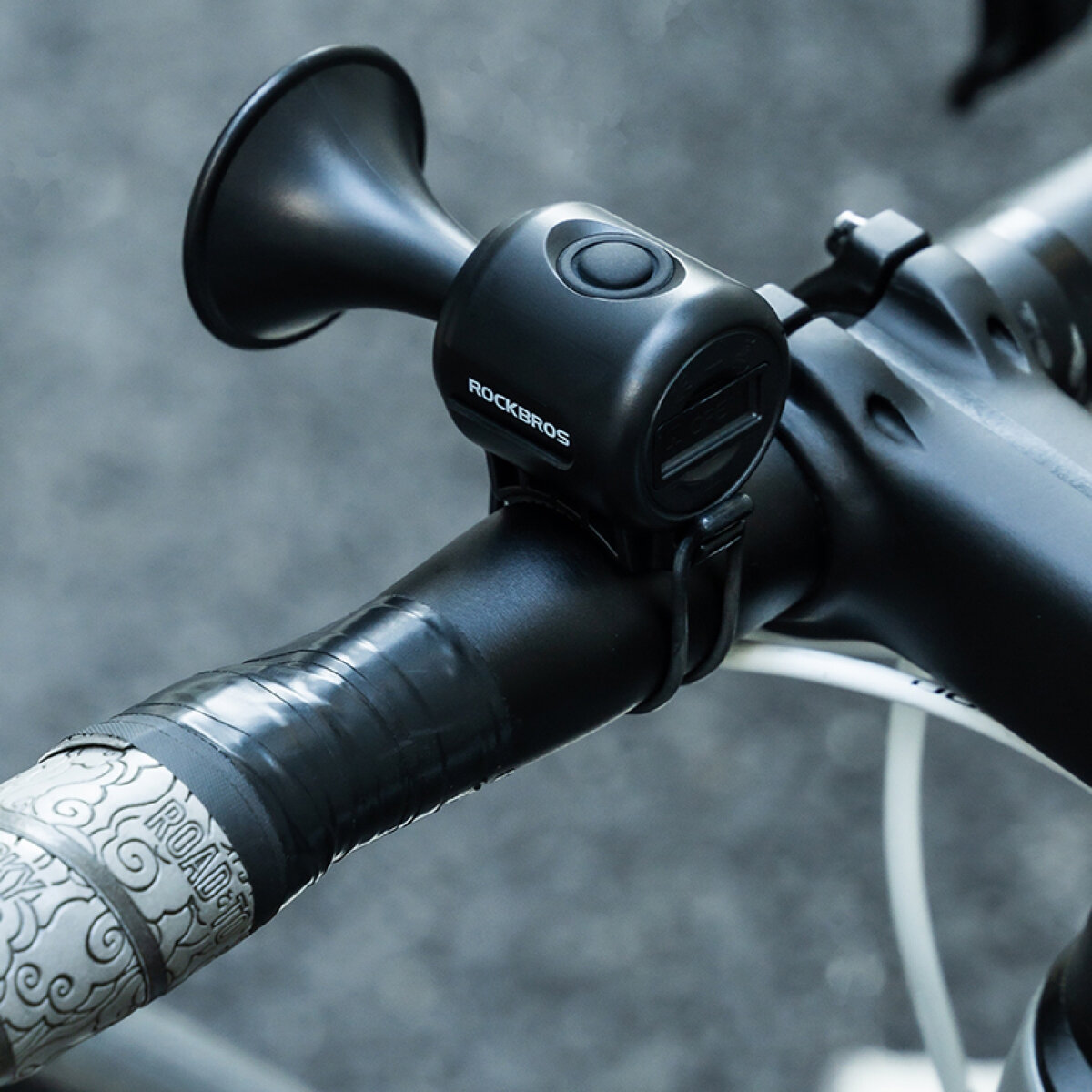 Elektryczny dzwonek rowerowy Rockbros zamontowany na kierownicy roweru, z widocznym logo \'ROCKBROS\'.