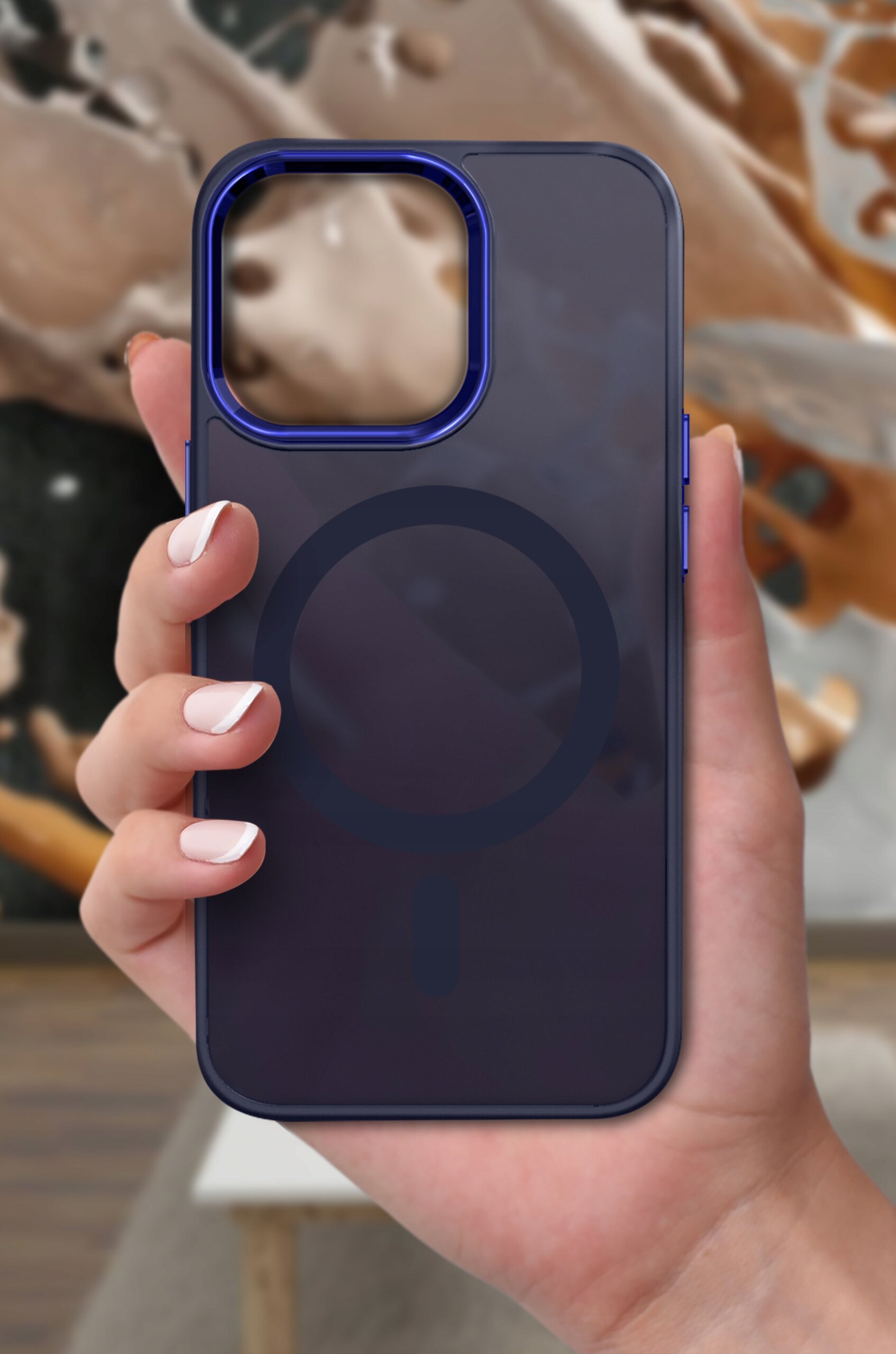 Osoba trzyma matowe etui na telefon z widocznym okrągłym wzorem na środku, na tle rozmytego wnętrza.
