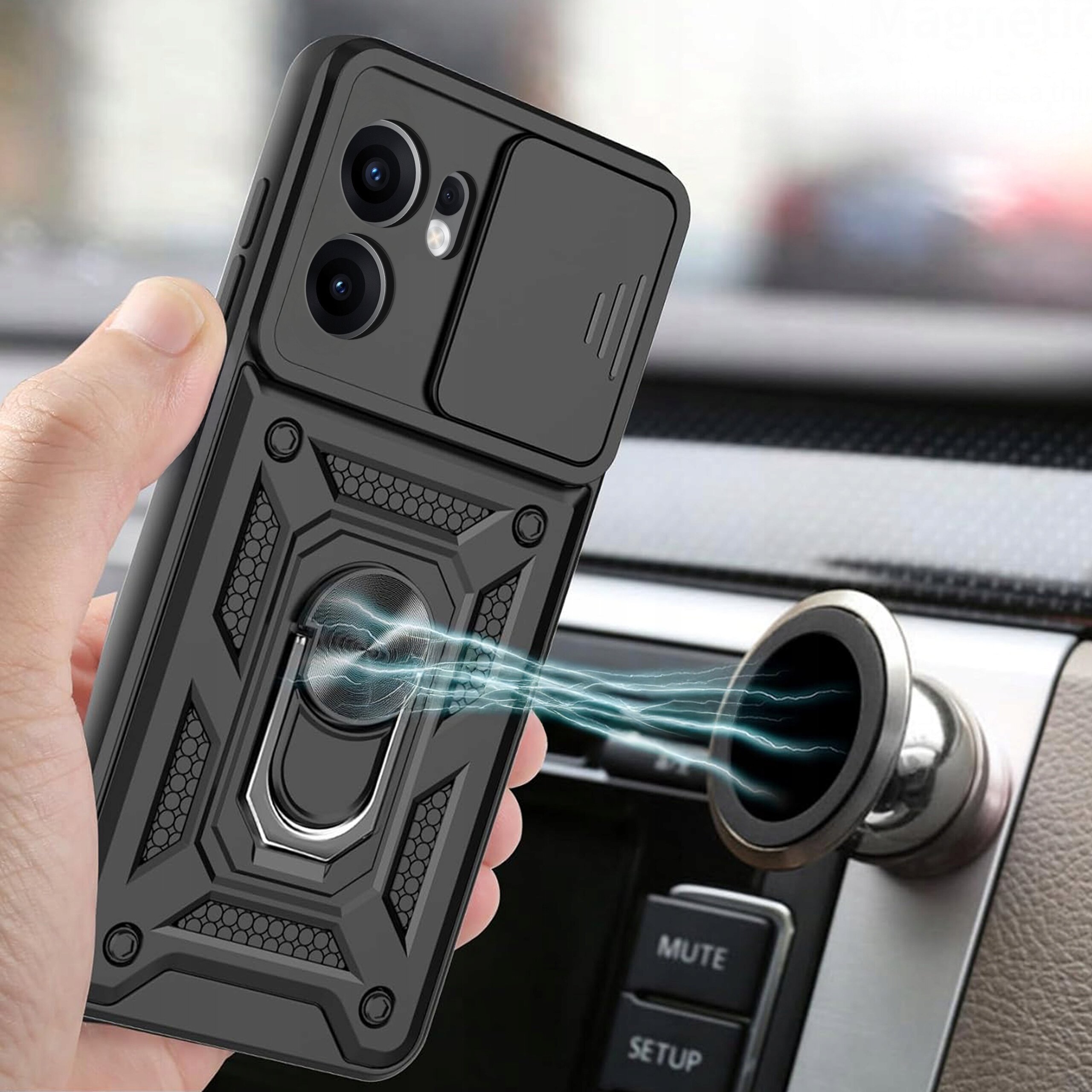 Osoba trzyma telefon w czarnym, pancernym etui z widocznym wzorem i metalowym uchwytem. W tle widać wnętrze samochodu z panelem sterowania i otworem wentylacyjnym.