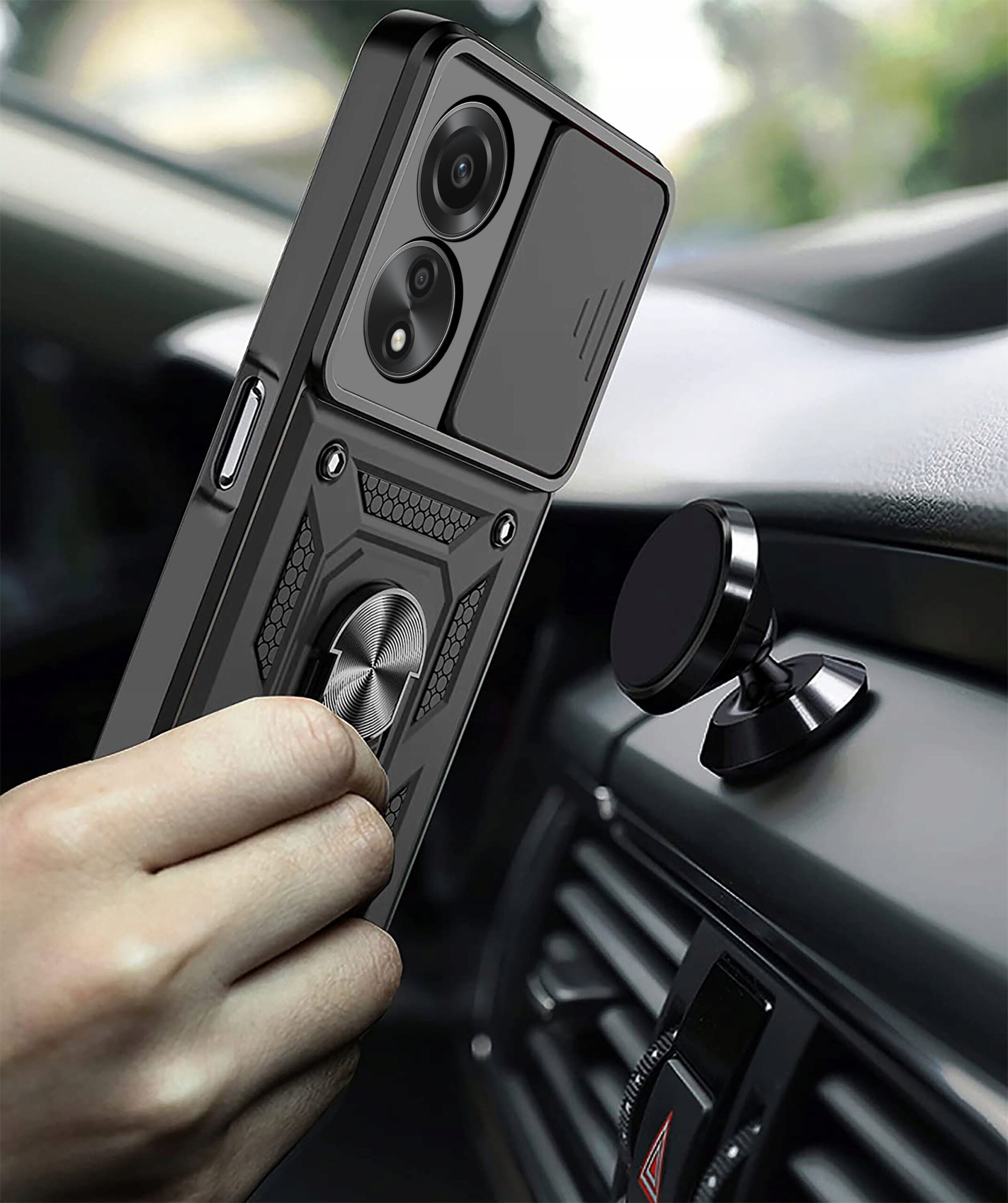 Osoba trzyma telefon w pancernym etui z pierścieniem, zbliżając go do magnetycznego uchwytu w samochodzie. Etui ma teksturowaną powierzchnię i dwa widoczne obiektywy aparatu.