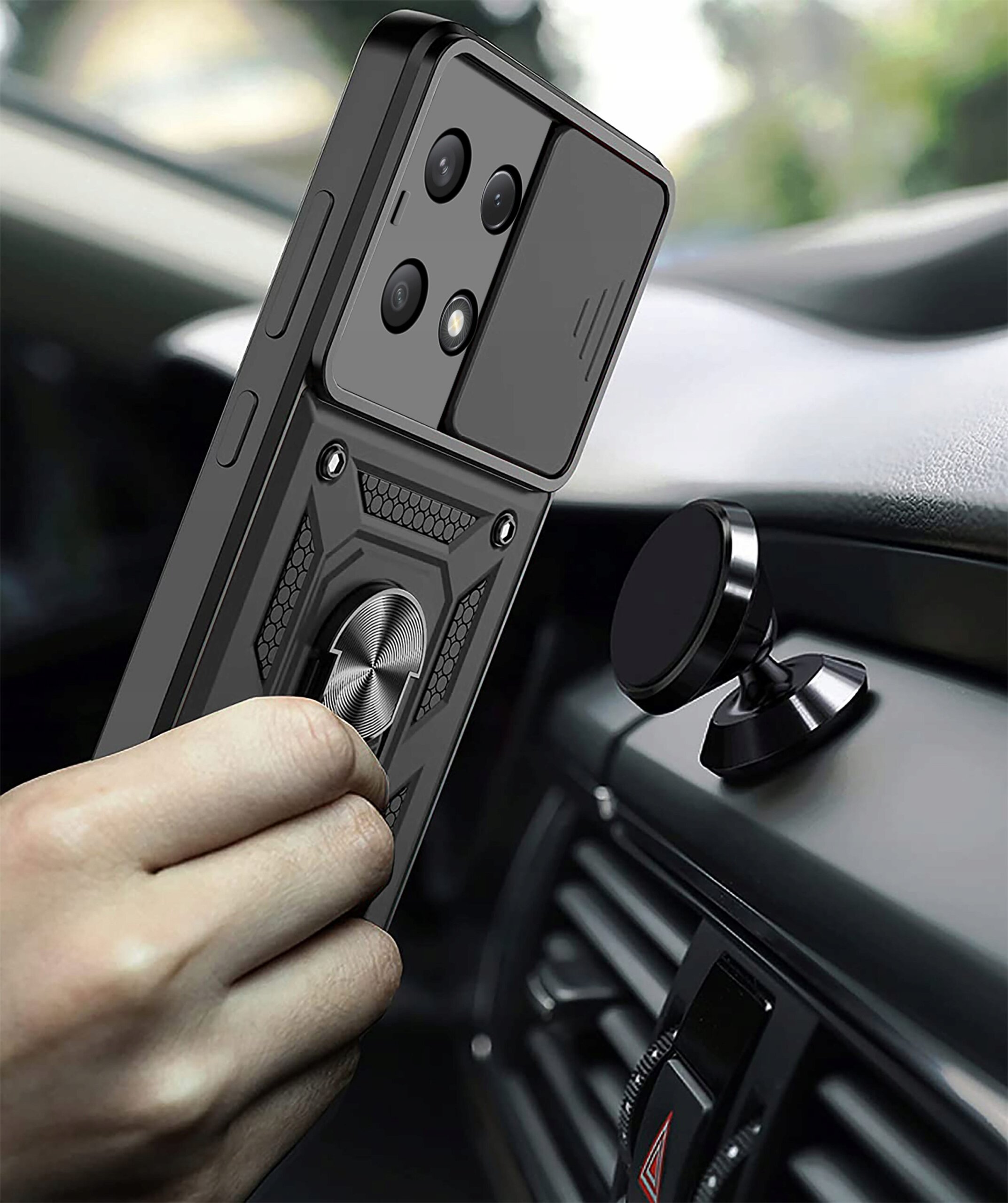 Osoba trzyma telefon w pancernym etui z pierścieniem, zbliżając go do magnetycznego uchwytu w samochodzie. Etui ma teksturowaną powierzchnię i widoczne są trzy obiektywy aparatu.