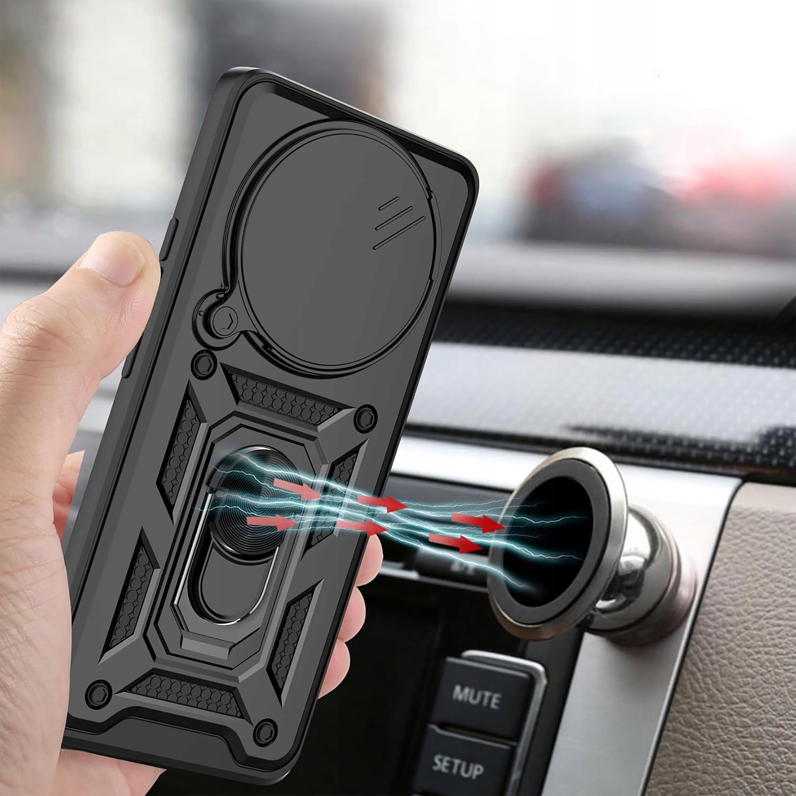 Osoba trzyma czarne etui na telefon z okrągłym uchwytem i wzorem geometrycznym, skierowane w stronę magnetycznego uchwytu samochodowego. W tle widoczne są elementy wnętrza samochodu, w tym przyciski z napisami \'MUTE\' i \'SETUP\'.