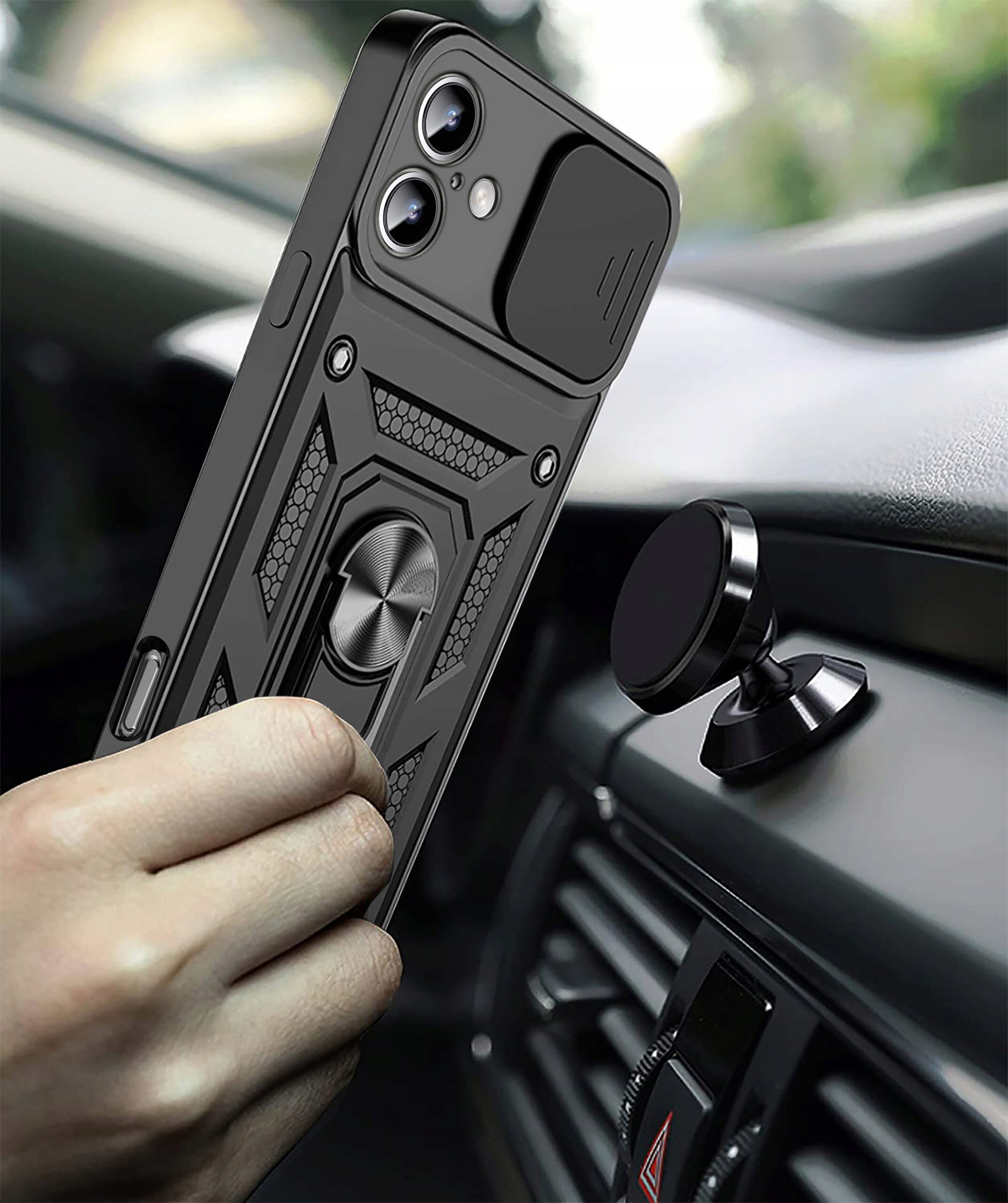 Osoba trzyma telefon w czarnym, pancernym etui z pierścieniem na tylnej części, w pobliżu magnetycznego uchwytu samochodowego. Etui ma wzmacniane krawędzie i teksturowane elementy dekoracyjne.