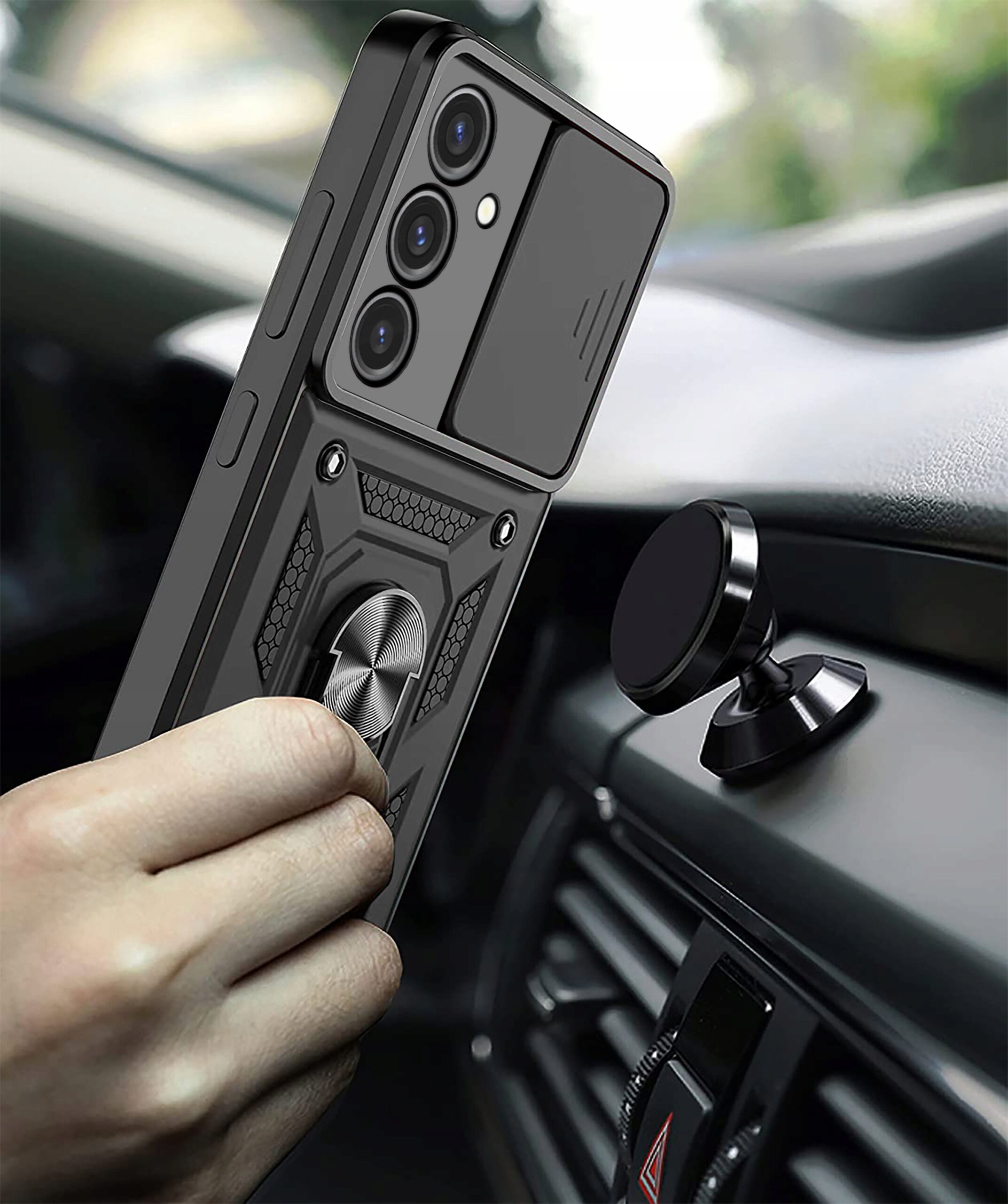 Osoba trzyma telefon w pancernym etui z pierścieniem, w pobliżu magnetycznego uchwytu samochodowego. Etui ma wzmacnianą konstrukcję i widoczne są trzy obiektywy aparatu.