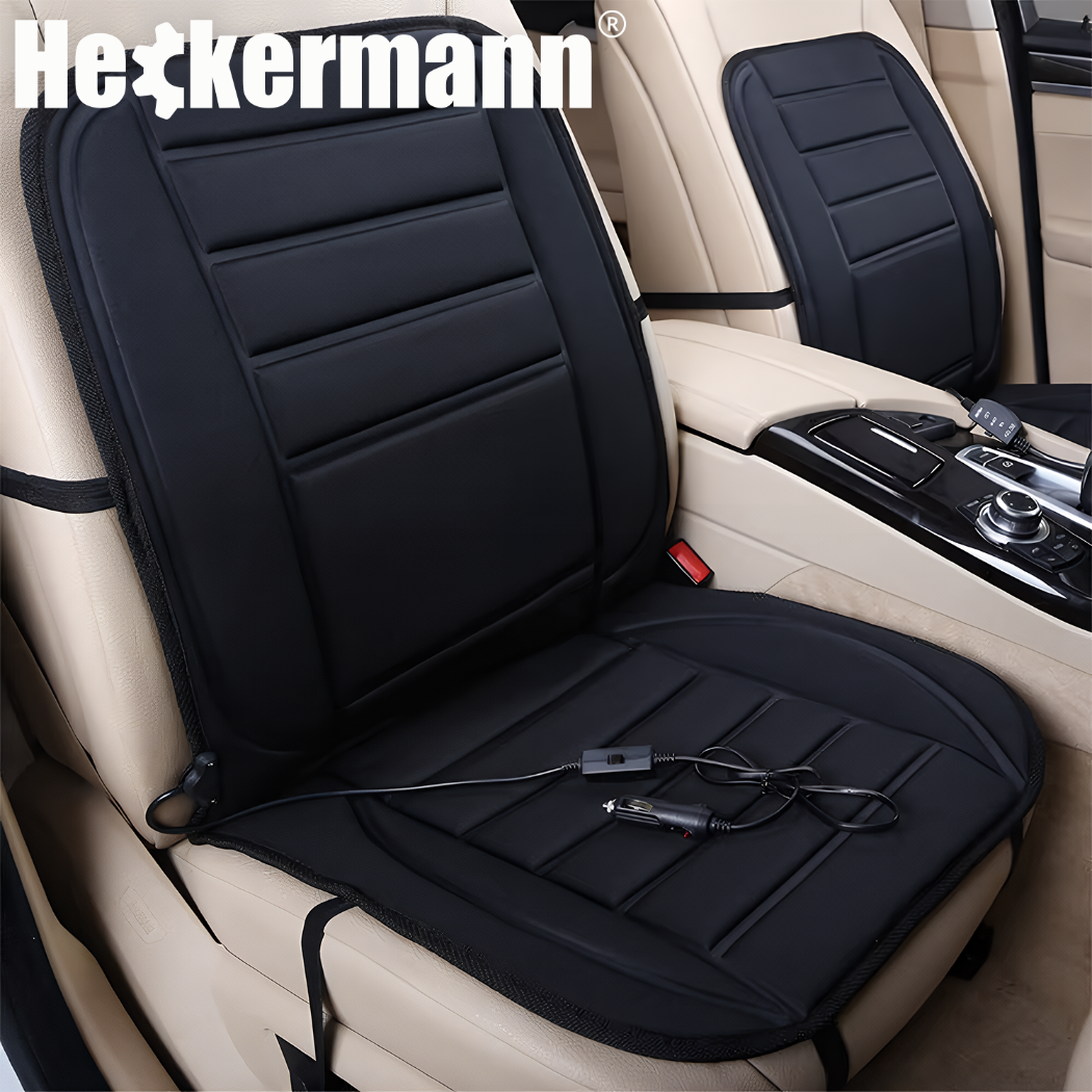 Czarna mata grzewcza umieszczona na jasnym fotelu samochodowym z widocznym przewodem zasilającym. Na górze obrazu znajduje się logo \'Heckermann\'.