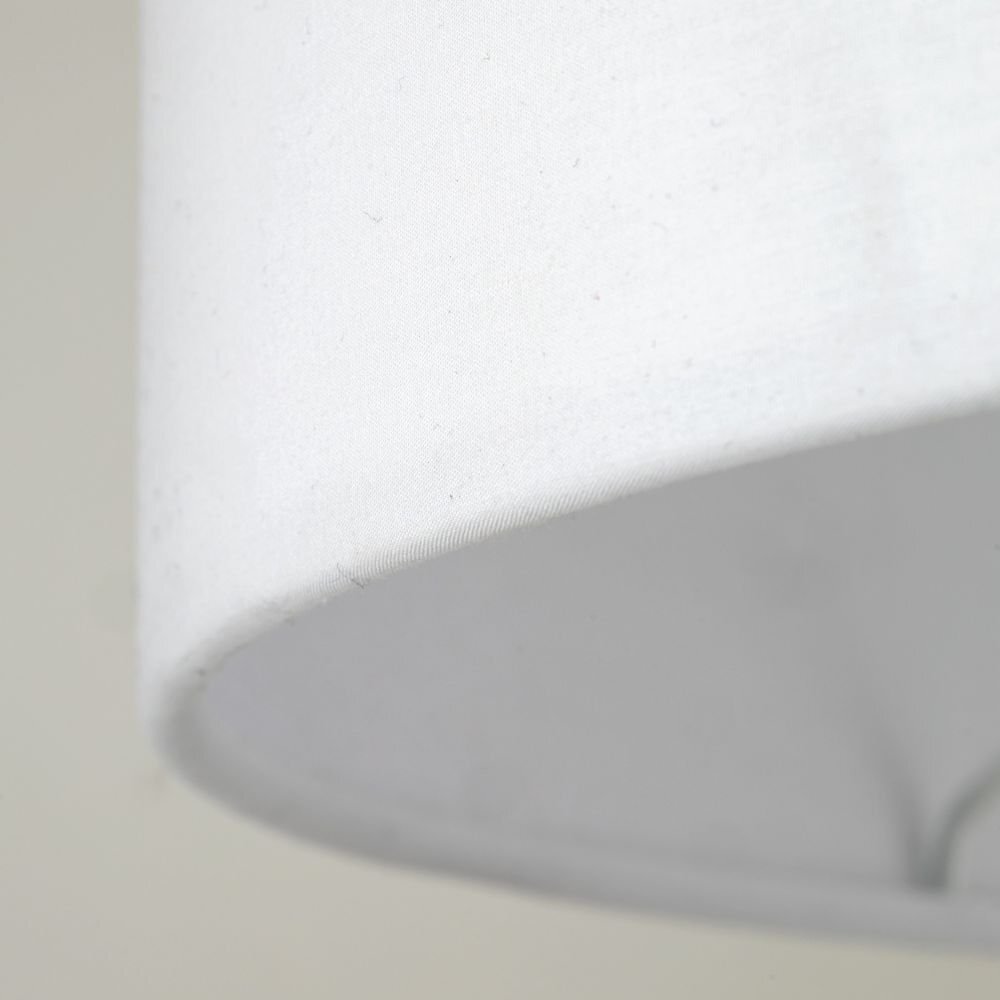 Zbliżenie na biały klosz lampy podłogowej z widoczną teksturą materiału.
