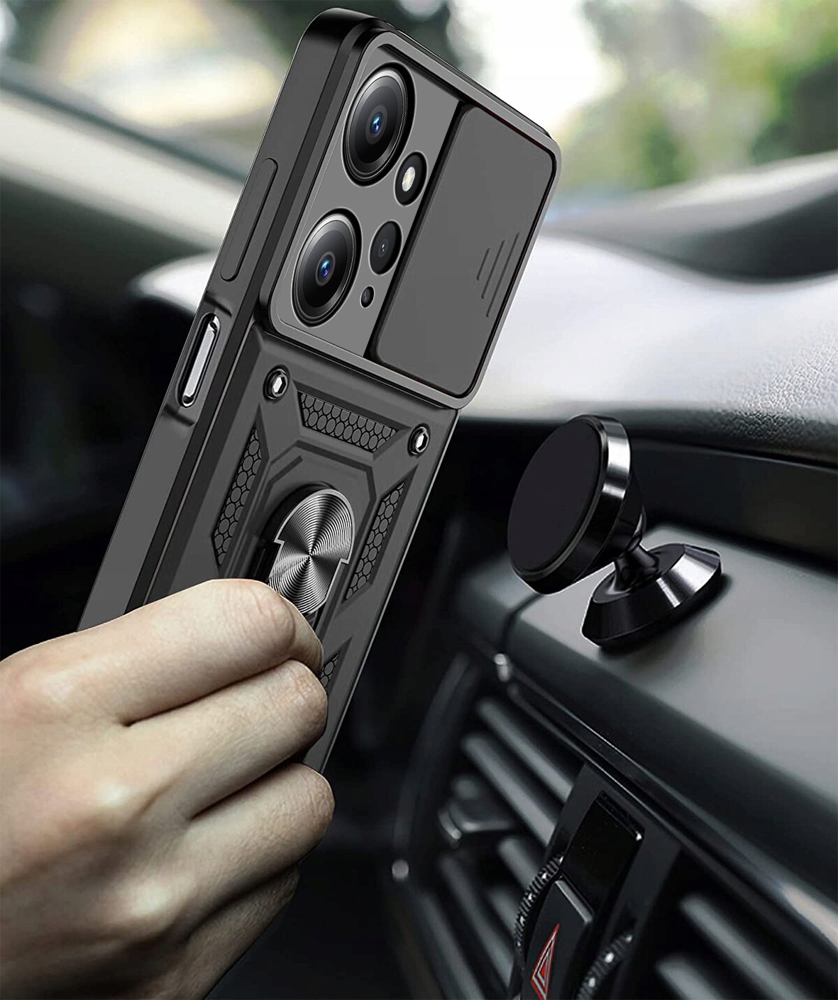 Osoba trzyma telefon w pancernym etui z widocznymi trzema obiektywami aparatu i metalowym pierścieniem na tylnej części. Telefon znajduje się w pobliżu magnetycznego uchwytu samochodowego zamontowanego na desce rozdzielczej.
