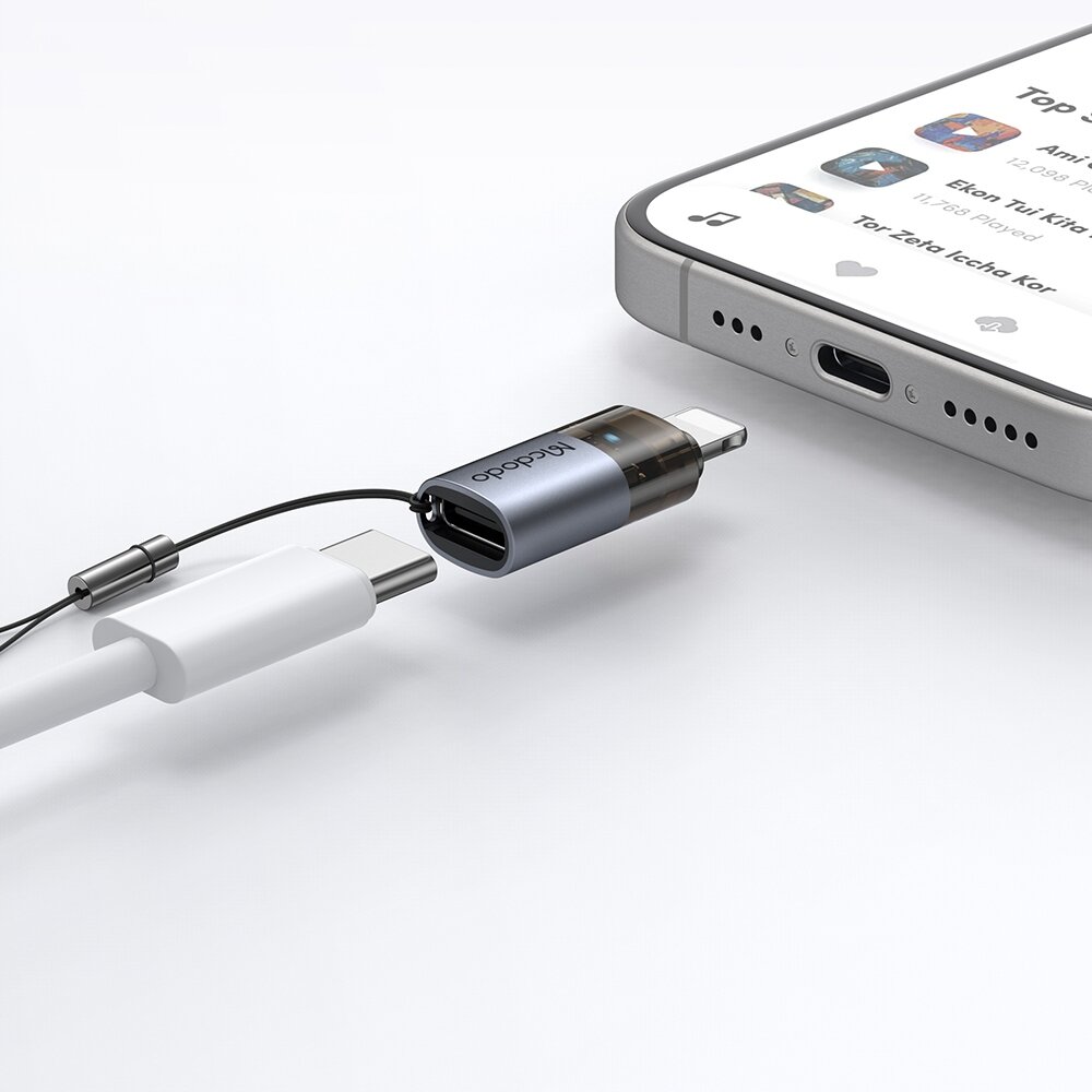 Adapter Mcdodo USB-C do Lightning z napisem \'Mcdodo\' jest podłączony do kabla USB-C i leży obok smartfona z widocznym ekranem aplikacji muzycznej.