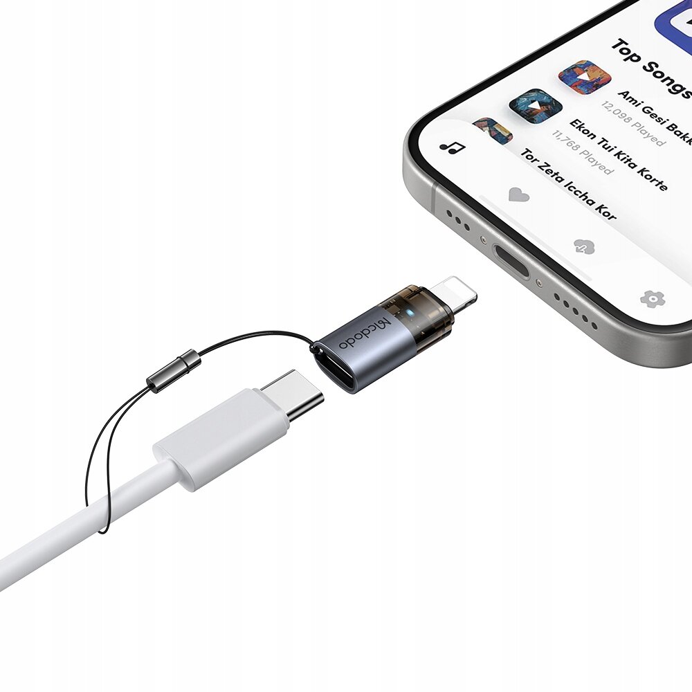Na obrazie widać adapter z logo \'Mcdodo\', który łączy kabel USB-C z portem Lightning w smartfonie. Ekran telefonu wyświetla aplikację muzyczną z listą utworów.