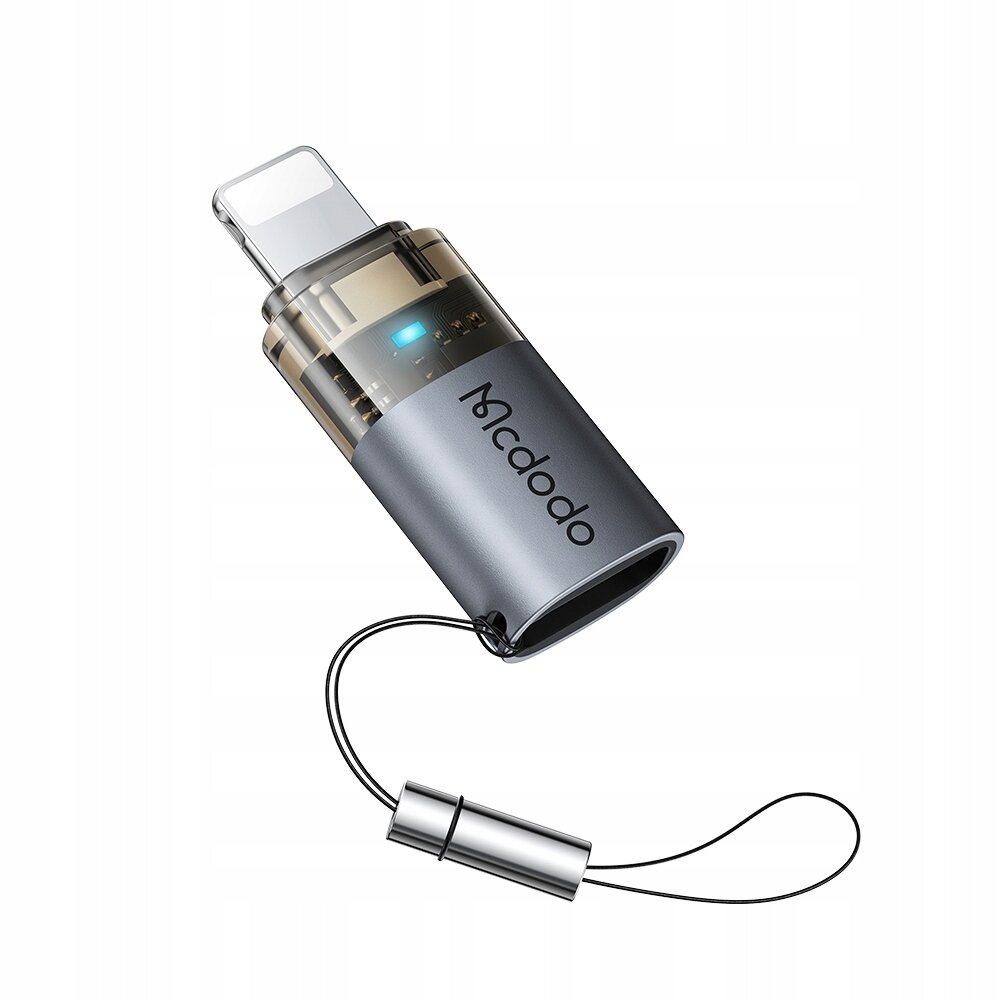 Na obrazie widoczny jest adapter USB-C do Lightning z logo \'Mcdodo\'. Adapter ma metaliczną obudowę i przezroczystą część z widocznymi elementami elektronicznymi oraz niebieskim wskaźnikiem LED.