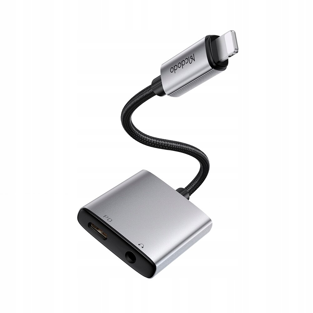 Na obrazie znajduje się adapter z logo \'Mcdodo\', posiadający złącze Lightning oraz porty mini jack 3,5 mm i PD. Adapter ma srebrny kolor i elastyczny, czarny kabel.