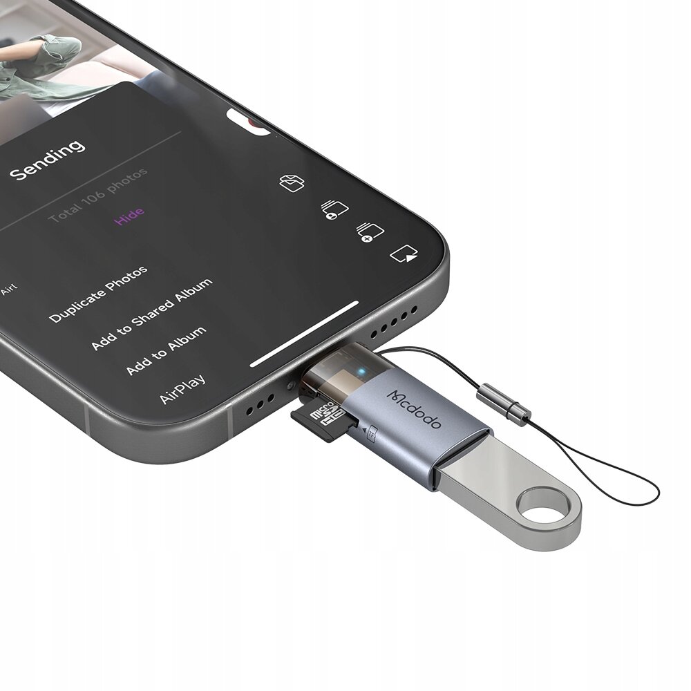 Adapter Mcdodo podłączony do smartfona z widocznym ekranem aplikacji do przesyłania zdjęć, z tekstem \'Sending\', \'Total 106 photos\', \'Hide\', \'Duplicate Photos\', \'Add to Shared Album\', \'Add to Album\', \'AirPlay\'.