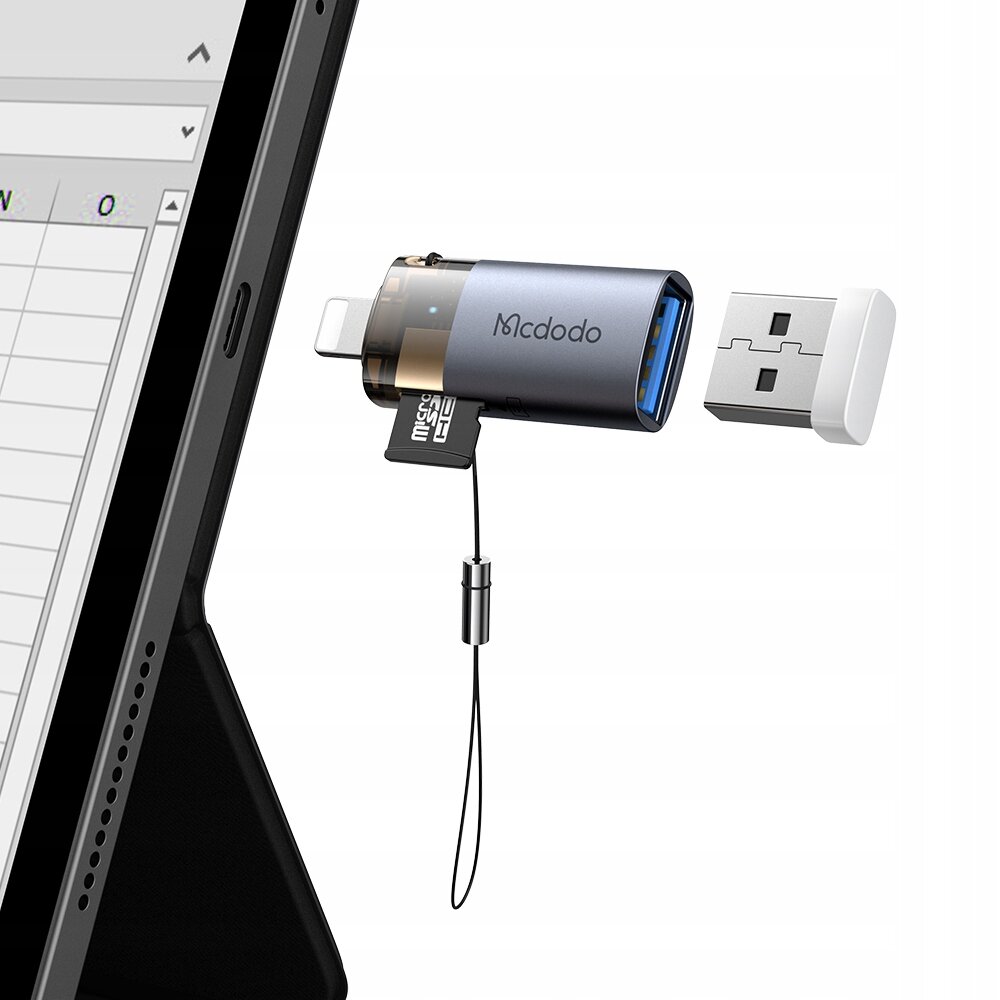 Na obrazie widoczny jest adapter Mcdodo z wtykiem USB-A i złączem Lightning, podłączony do tabletu. Obok adaptera znajduje się odłączona wtyczka USB oraz karta microSD wsunięta do adaptera.