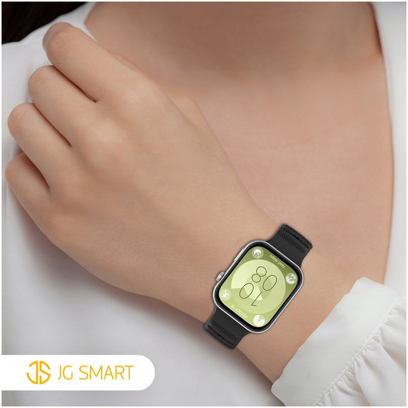 Osoba nosi smartwatch z czarnym silikonowym paskiem na nadgarstku. W lewym dolnym rogu widoczne jest logo \'JG SMART\'.