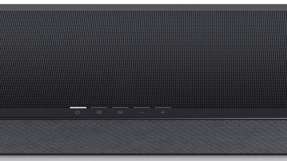 Czarny soundbar z widocznymi przyciskami na panelu przednim, w tym przyciskiem zasilania, ikoną ekranu, przyciskami odtwarzania oraz regulacji głośności. Powierzchnia pokryta jest siatką ochronną.
