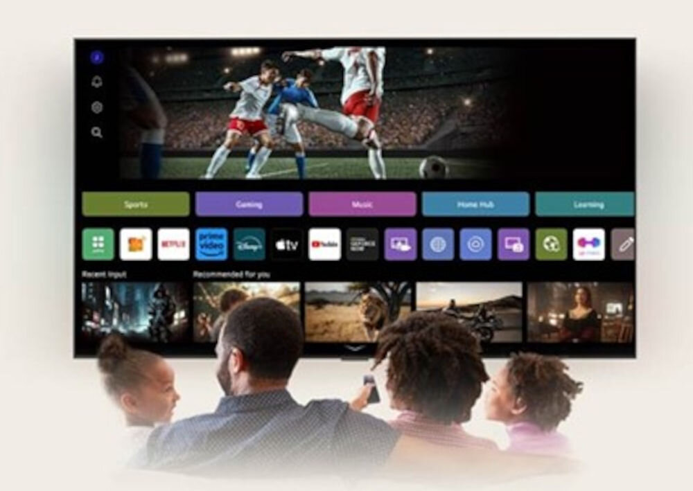 Telewizor wyświetla mecz piłki nożnej oraz interfejs z aplikacjami takimi jak Netflix, Prime Video, Disney+, iTV, YouTube. Przed ekranem siedzą cztery osoby oglądające program.