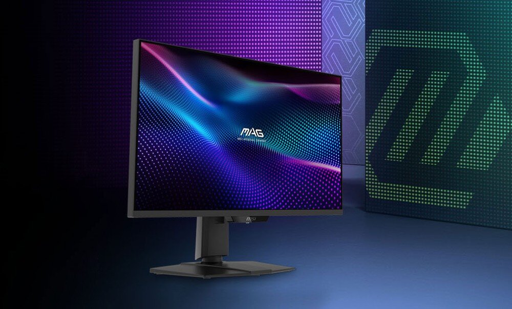 Monitor z logo \'MAG\' na ekranie, wyświetlający kolorowe, faliste wzory. W tle widoczne są geometryczne wzory i logo producenta.