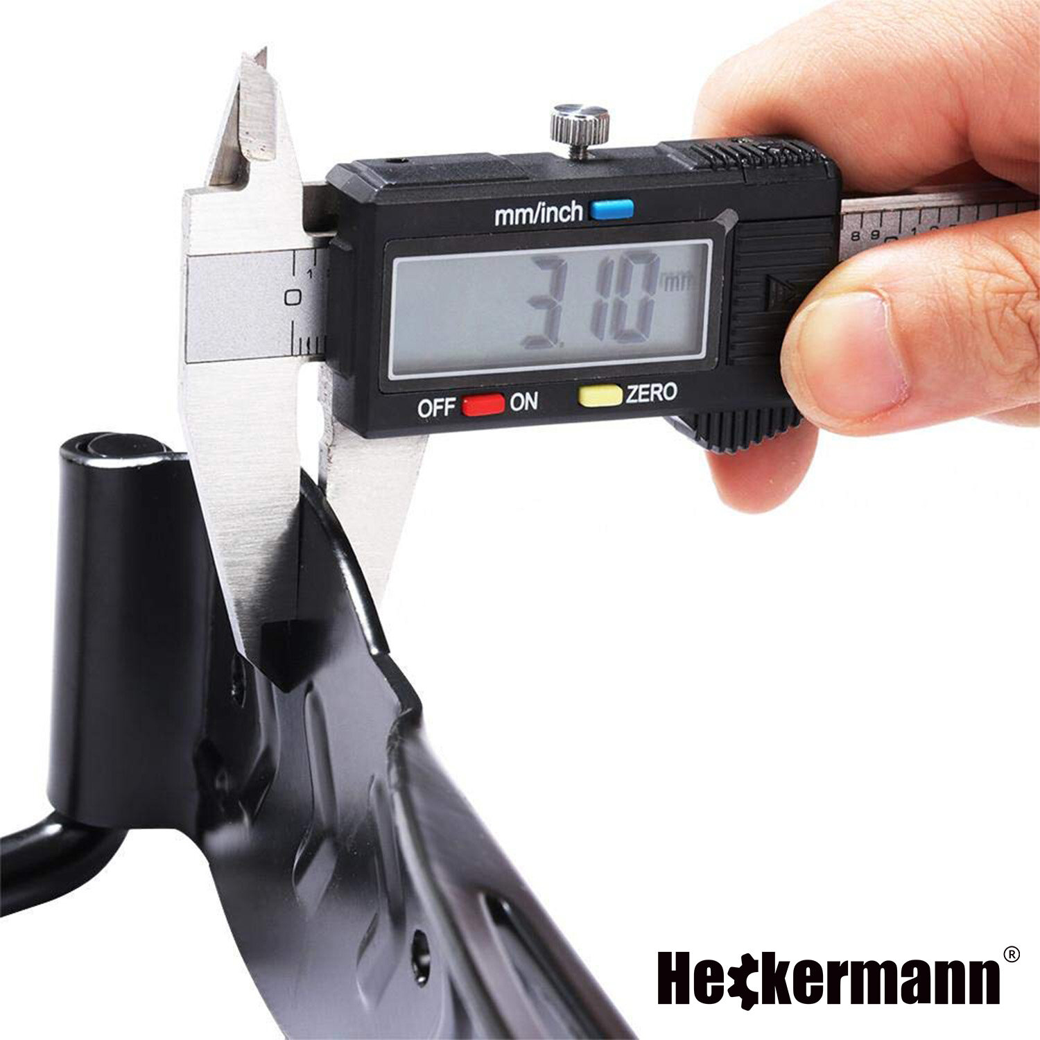 Na zdjęciu widać suwmiarkę mierzącą grubość metalowego elementu, wyświetlacz pokazuje 3.10 mm. W prawym dolnym rogu znajduje się logo \'Heckermann\'.