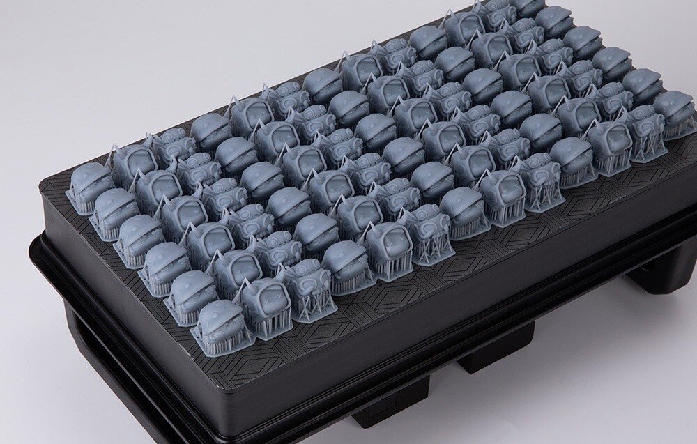 Drukarka 3D ELEGOO Jupiter 2 Platforma robocza drukarki 3D zapełniona dziesiątkami małych, seryjnie wydrukowanych figurek z żywicy, źródło światła, utwardzanie