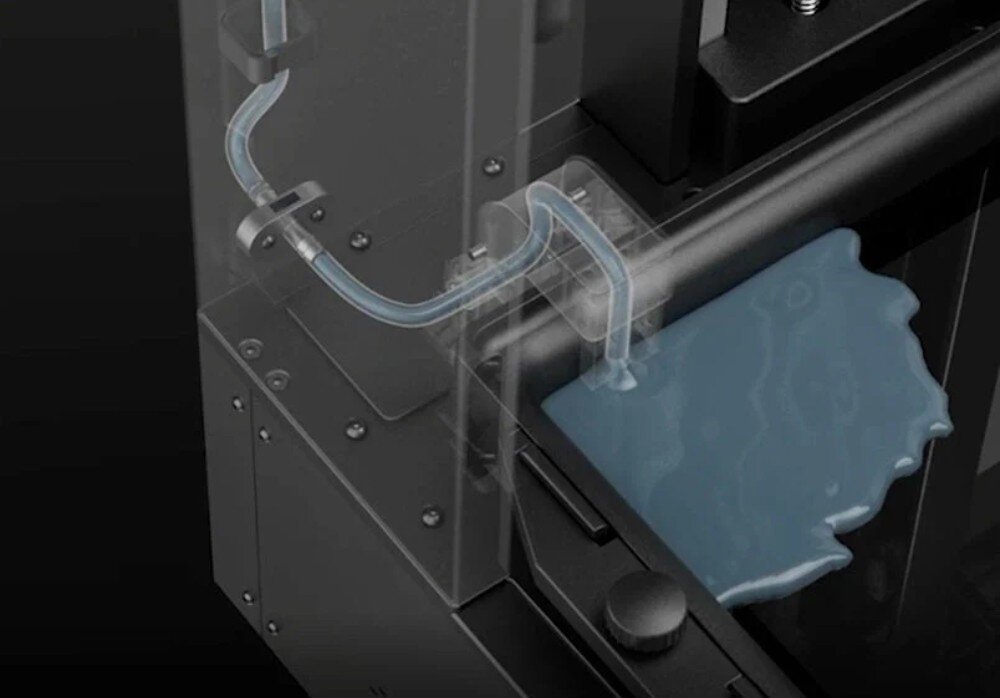 Drukarka 3D ELEGOO Jupiter 2 Przezroczysta rurka transportująca płyn do prostokątnego pojemnika wewnątrz mechanizmu, ukazana z bliska pod kątem, uzupełnianie materiału, dozowanie, odzysk