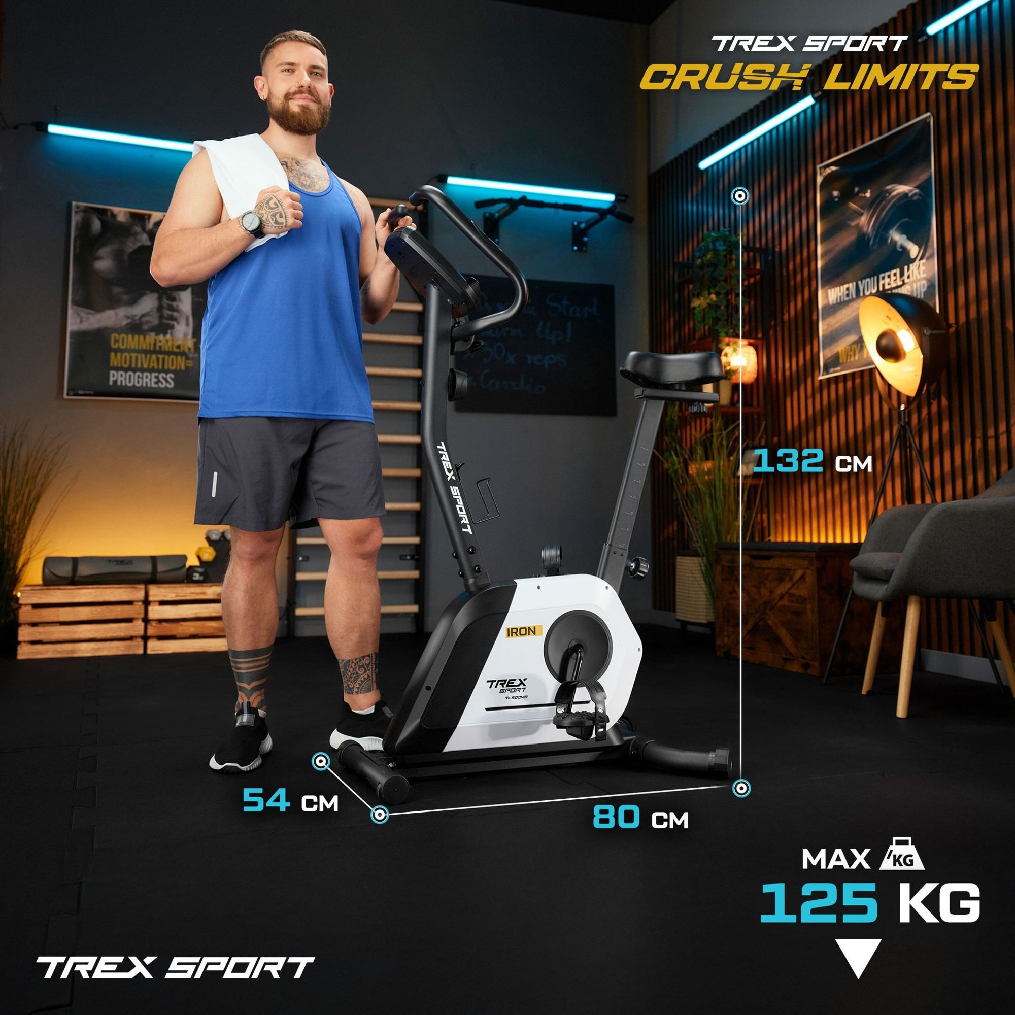 Na obrazie znajduje się rower stacjonarny magnetyczny IRON TX-500MB biały z oznaczeniami wymiarów: 54 cm, 80 cm, 132 cm oraz maksymalnym obciążeniem 125 kg. W tle widoczne są elementy wyposażenia siłowni oraz napisy: \'TREX SPORT\', \'CRUSH LIMITS\'.