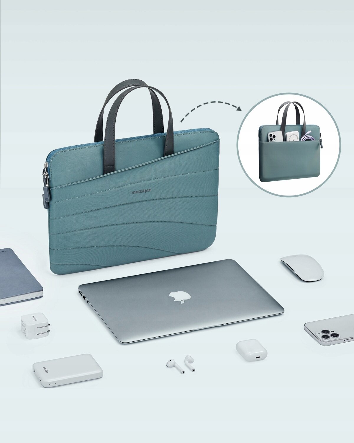 Zielona torba na laptopa z dwoma uchwytami i logo \'innostyle\' na środku. Wokół torby znajdują się akcesoria elektroniczne, takie jak laptop, myszka, telefon i słuchawki.