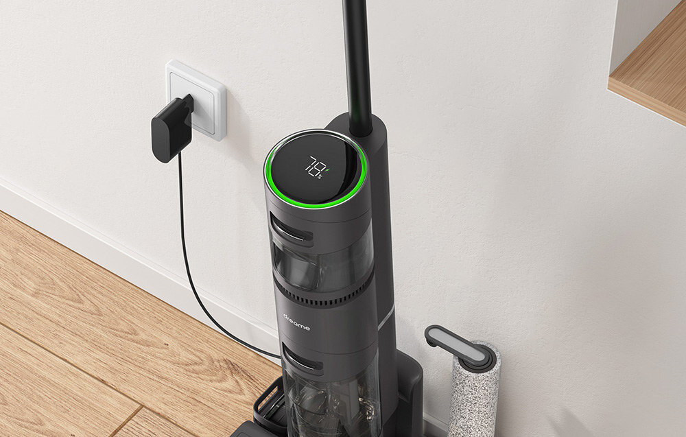 Na obrazie widoczny jest odkurzacz z mopem w kolorze ciemnoszarym, podłączony do gniazdka elektrycznego. Na górze urządzenia znajduje się wyświetlacz z cyframi \'78\' otoczony zielonym pierścieniem.