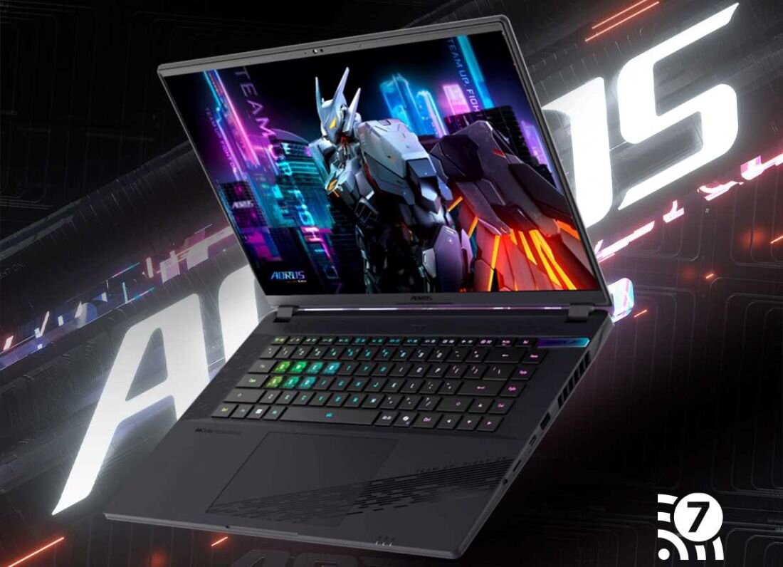 Laptop z kolorową klawiaturą i ekranem wyświetlającym futurystyczną grafikę robota. W tle widoczne jest logo \'AORUS\'.