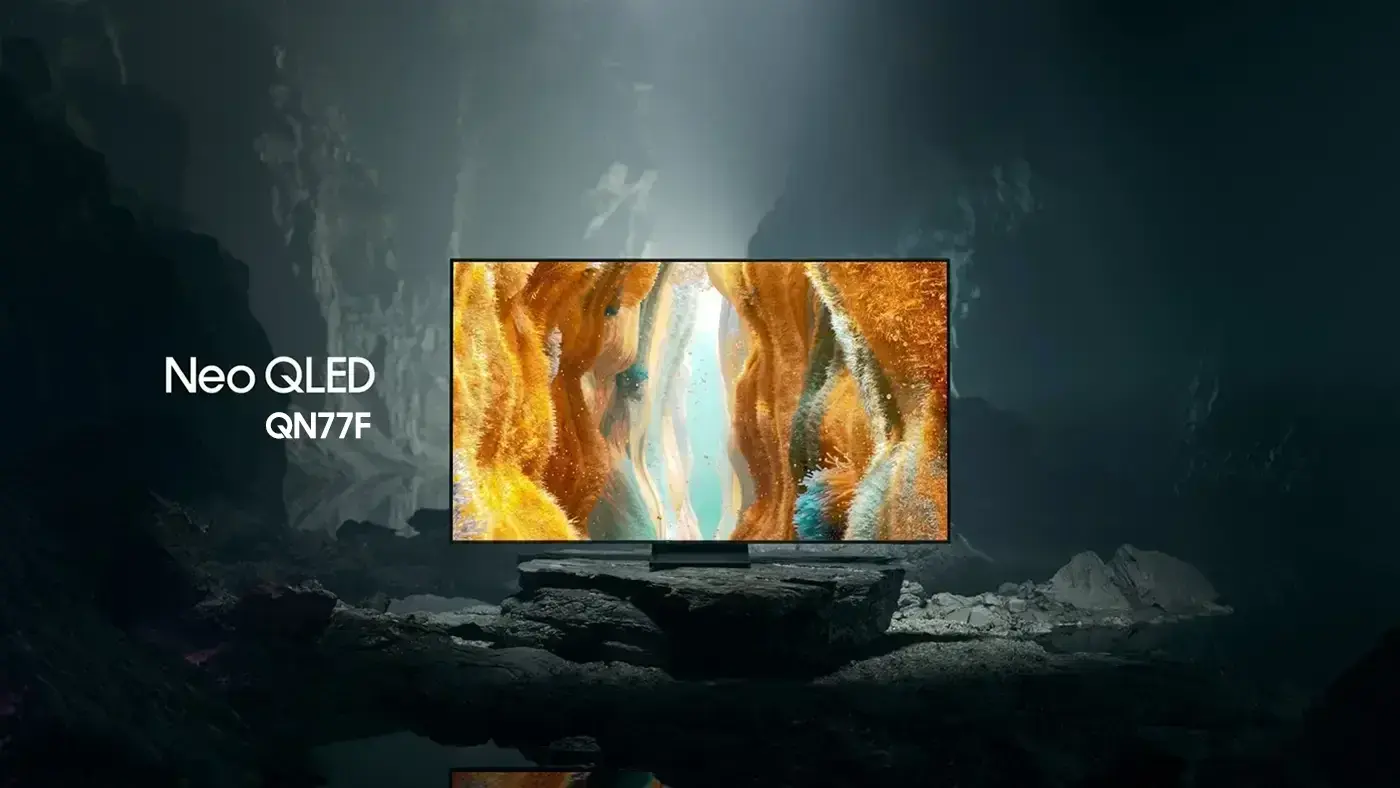1400x788 line-up-tech-demo qn77f Telewizor z wyświetlaczem pokazującym kolorowy, abstrakcyjny obraz, ustawiony na tle ciemnej, skalistej scenerii. Obok ekranu widoczny jest napis \'Neo QLED QN77F\'.