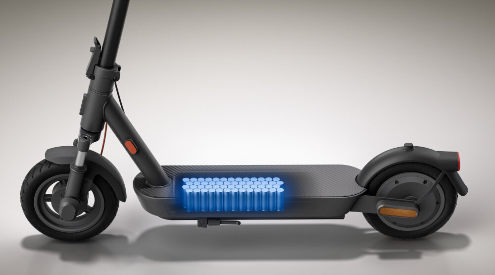 Obraz przedstawia czarną hulajnogę elektryczną z widocznym schematem baterii umieszczonej w platformie. Hulajnoga ma duże koła i minimalistyczny design.
